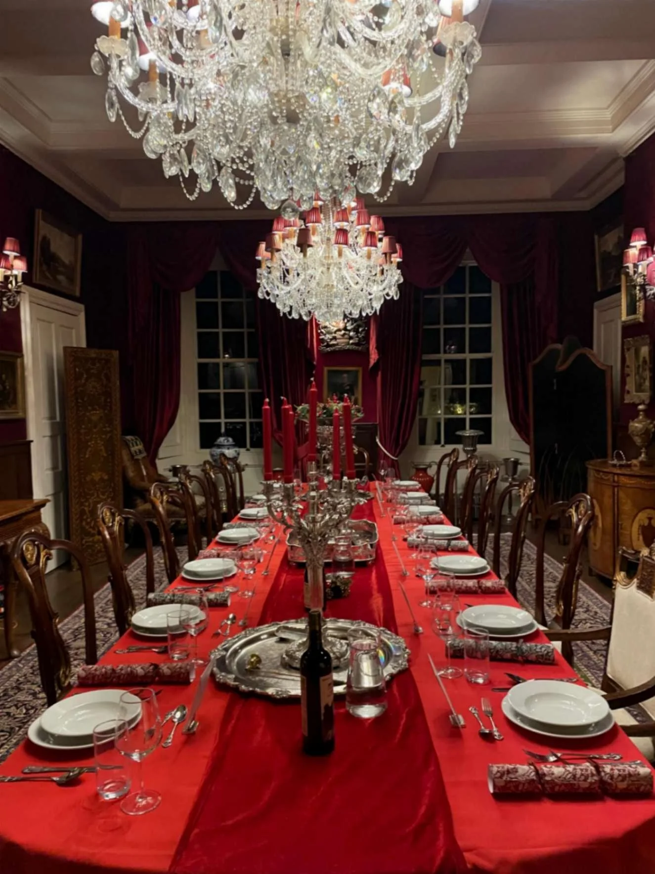Formal private dining table with red linen, silverware and chandeliers prepared for a Greek Tings event.