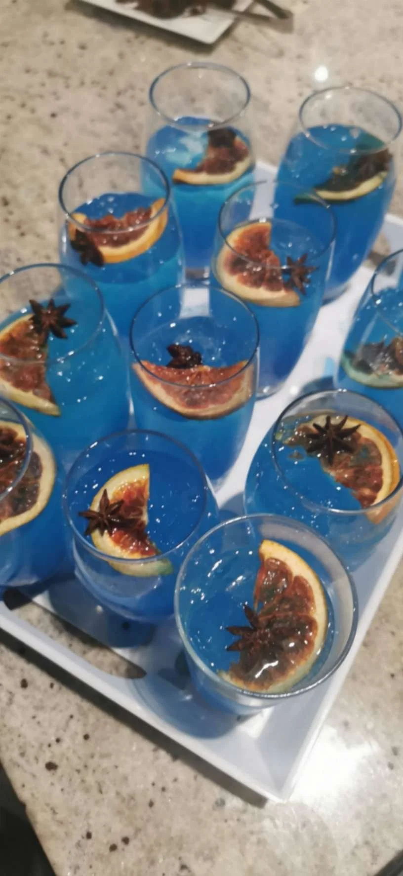 Tray of bright blue cocktails garnished with grapefruit slices and star anise for event drinks service.
