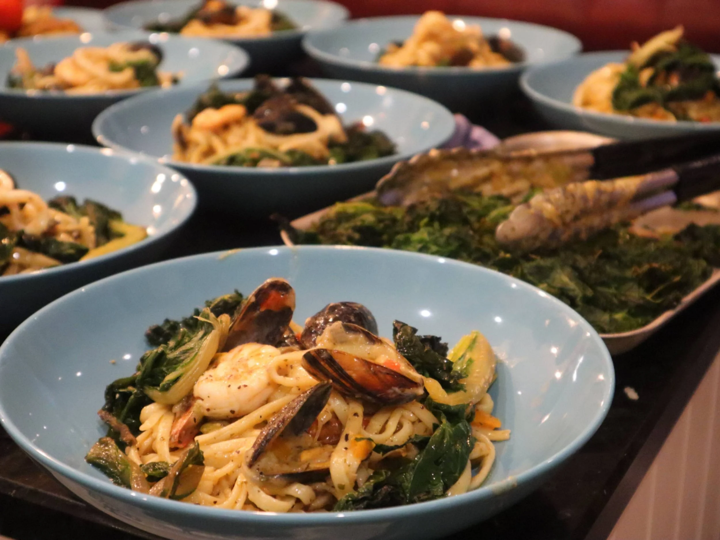 Bowls of seafood linguine with prawns and mussels ready for private dining service.