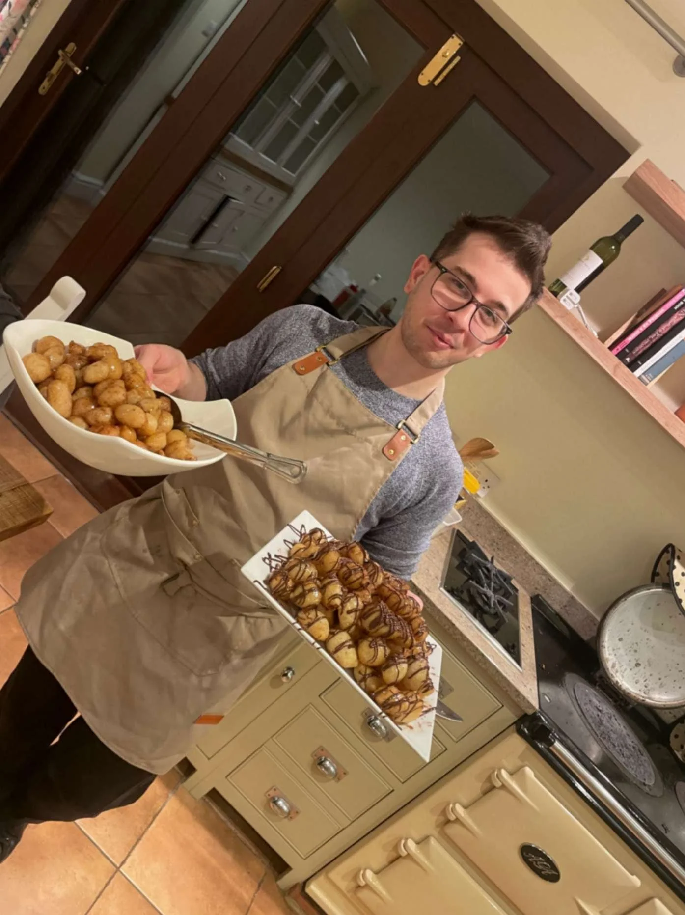 Greek Tings chef holding trays of roasted baby potatoes in a private kitchen.
