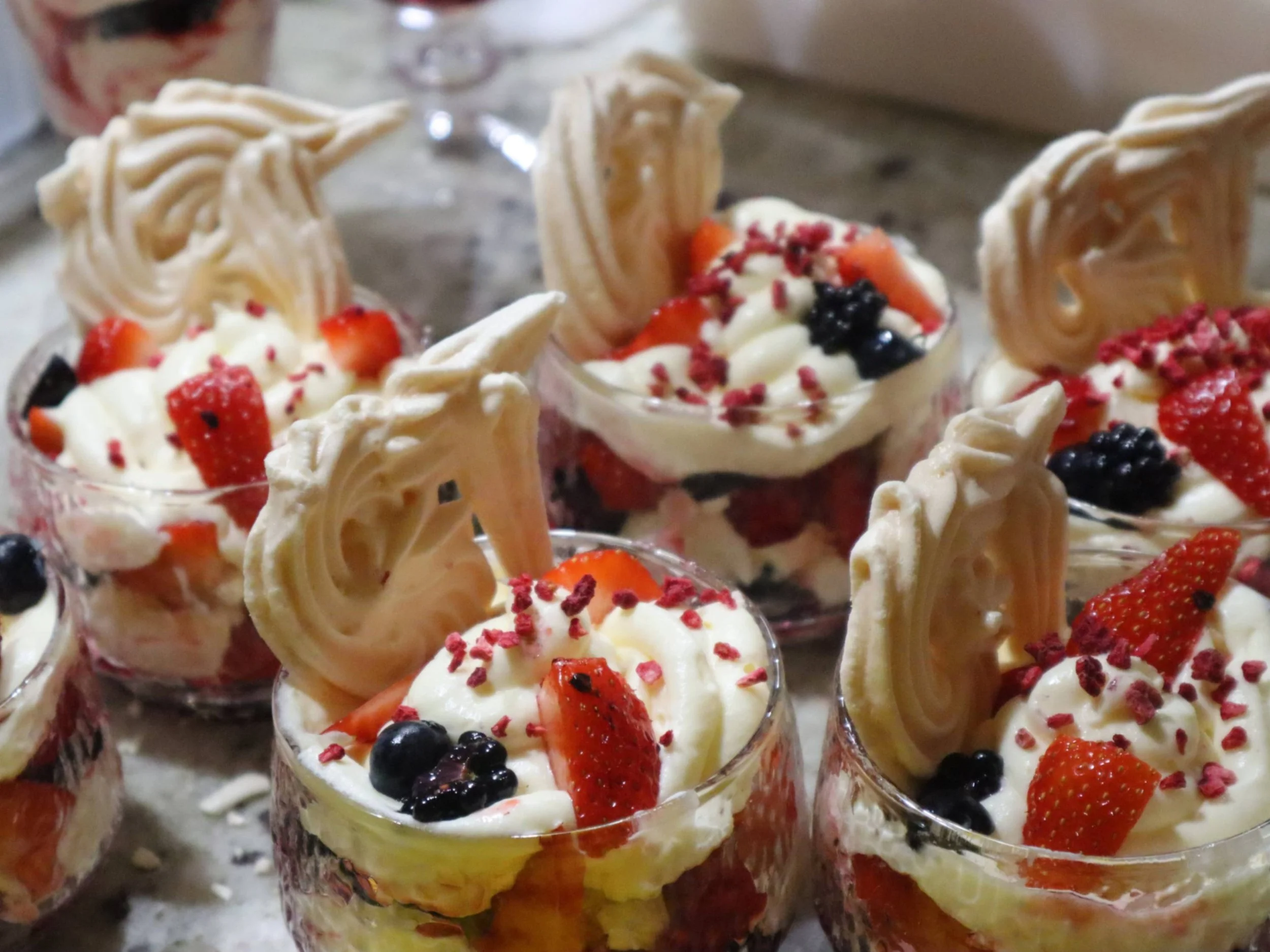 Berry and cream desserts topped with crisp meringue in individual glasses.