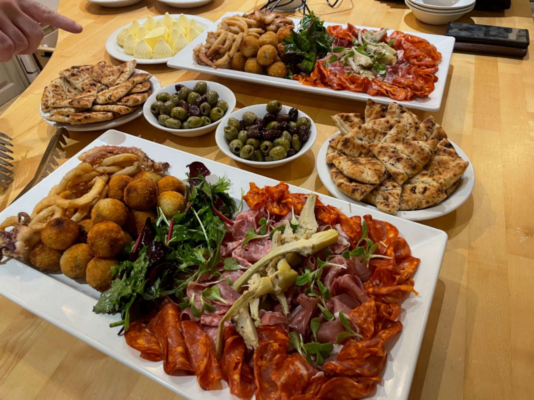 Large Italian sharing feast with cured meats, fried bites, salad, flatbread, olives and dips.