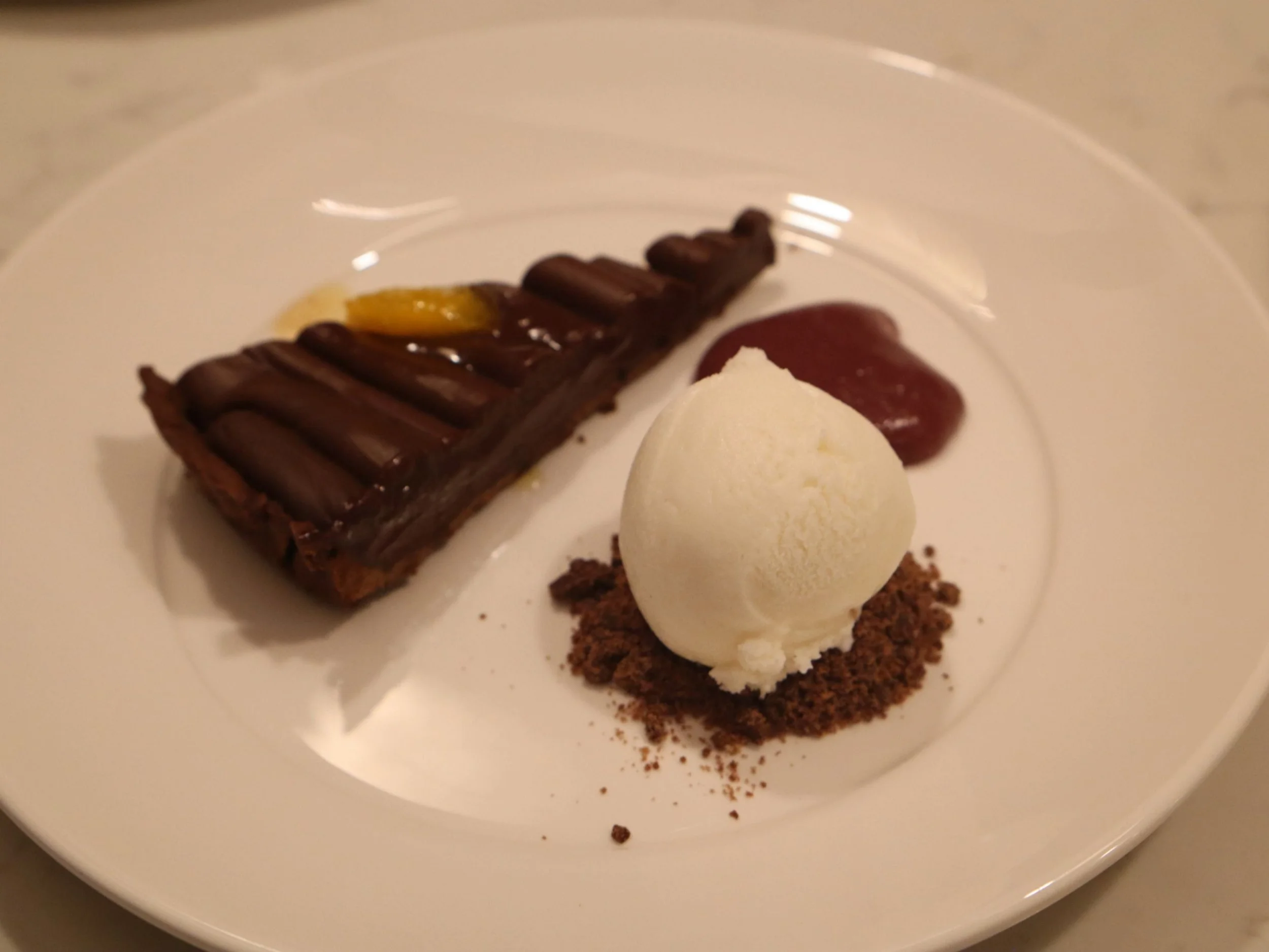 Chocolate tart served with vanilla ice cream, chocolate crumb and red fruit sauce.