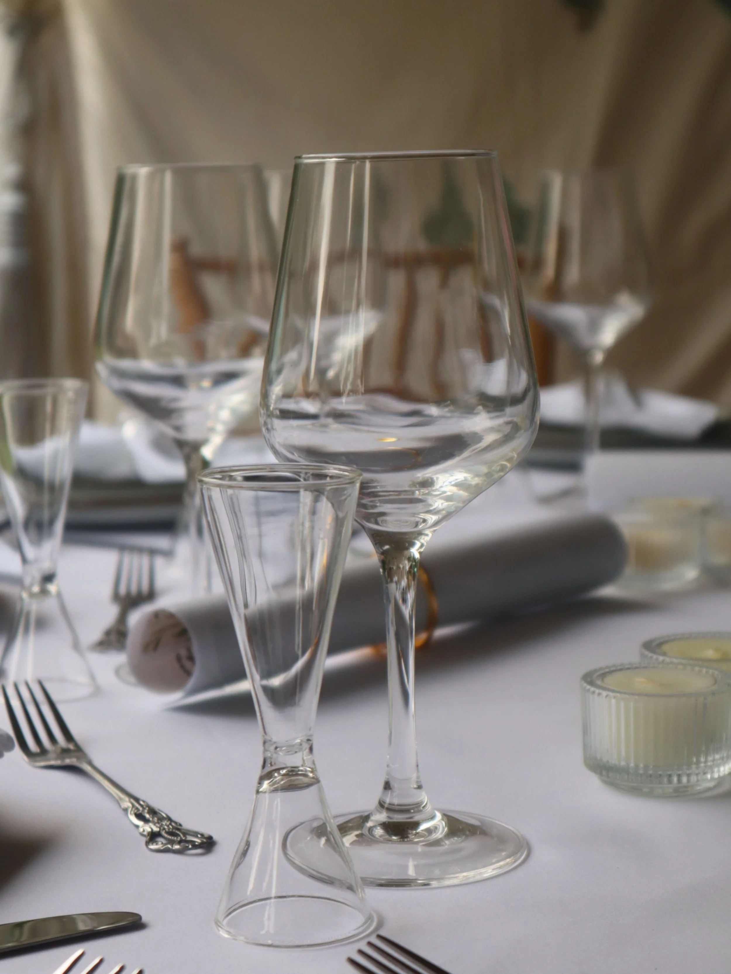 Wine glass and measuring glass among formal place settings at a Greek Tings event.
