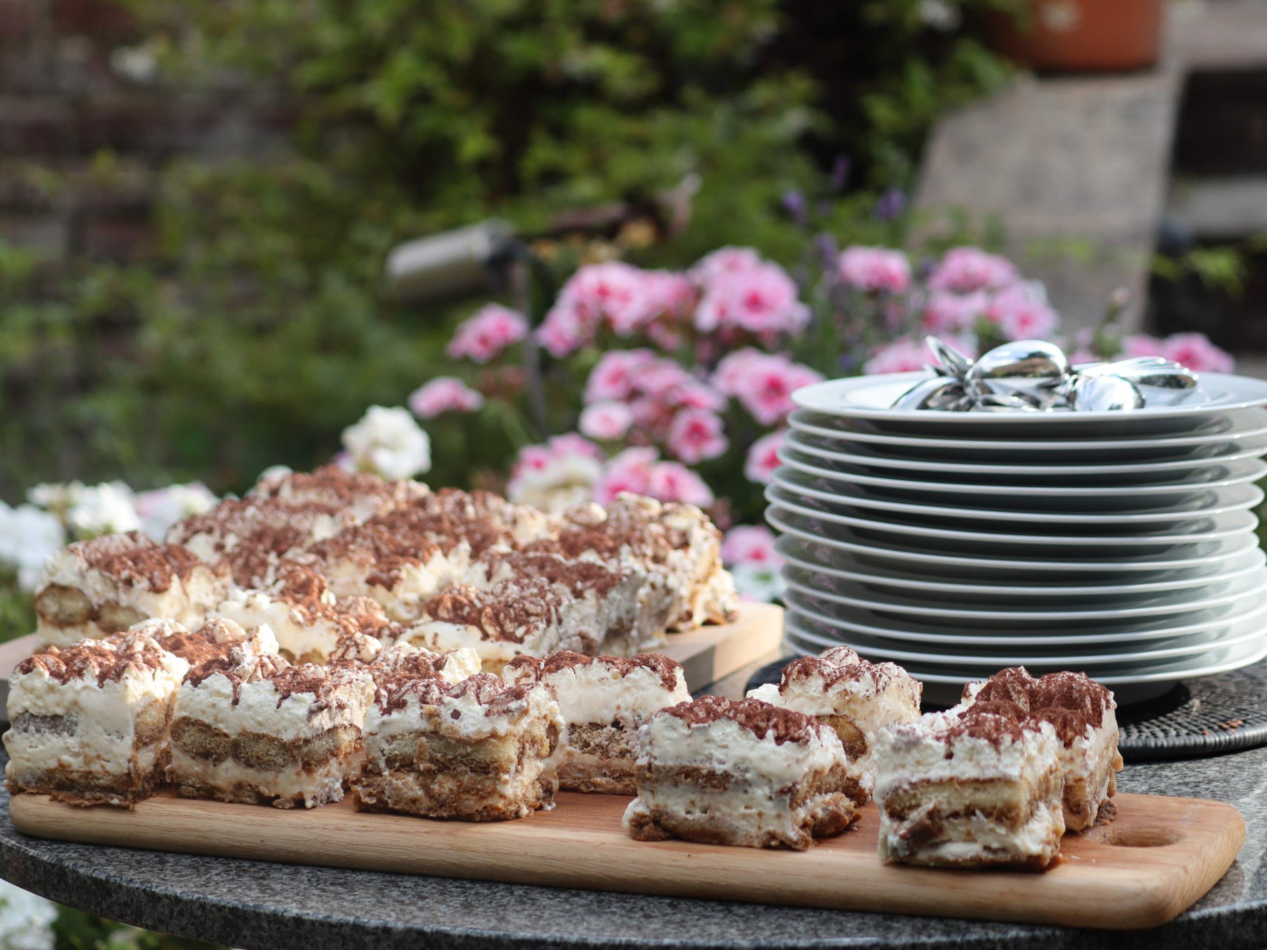 Tiramisu portions arranged beside plates for outdoor private dining service.