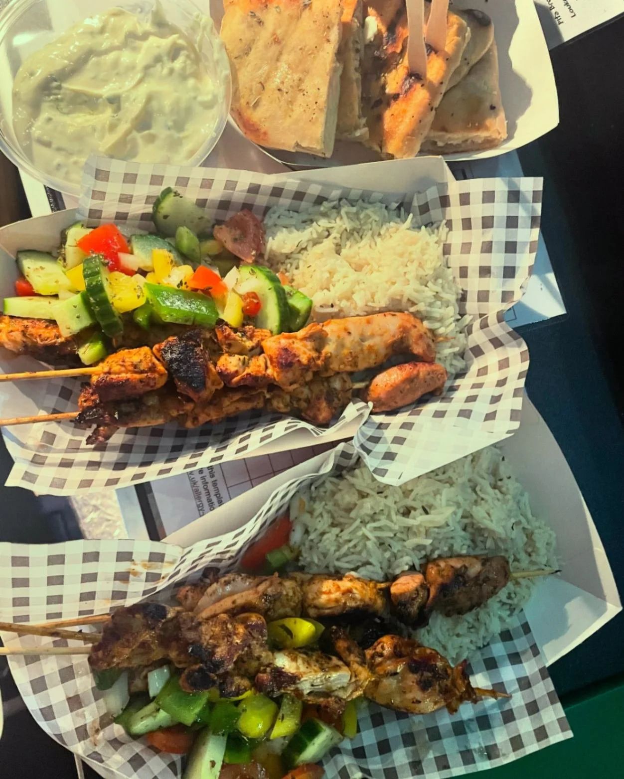 Greek souvlaki skewers with rice, grilled vegetables, pita and tzatziki served at a festival.

