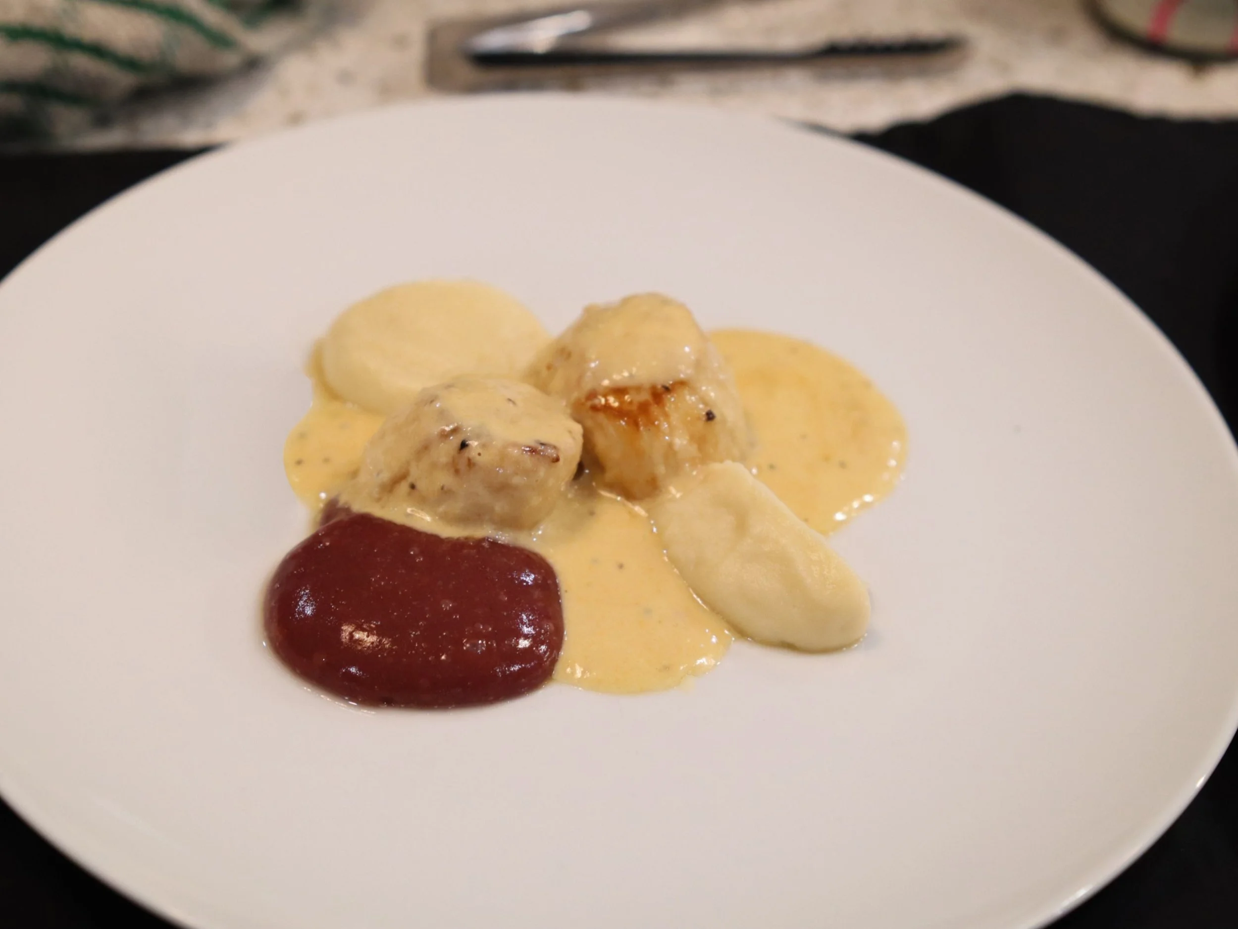 Plated scallops starter with creamy sauce, smooth puree and grape compote.
