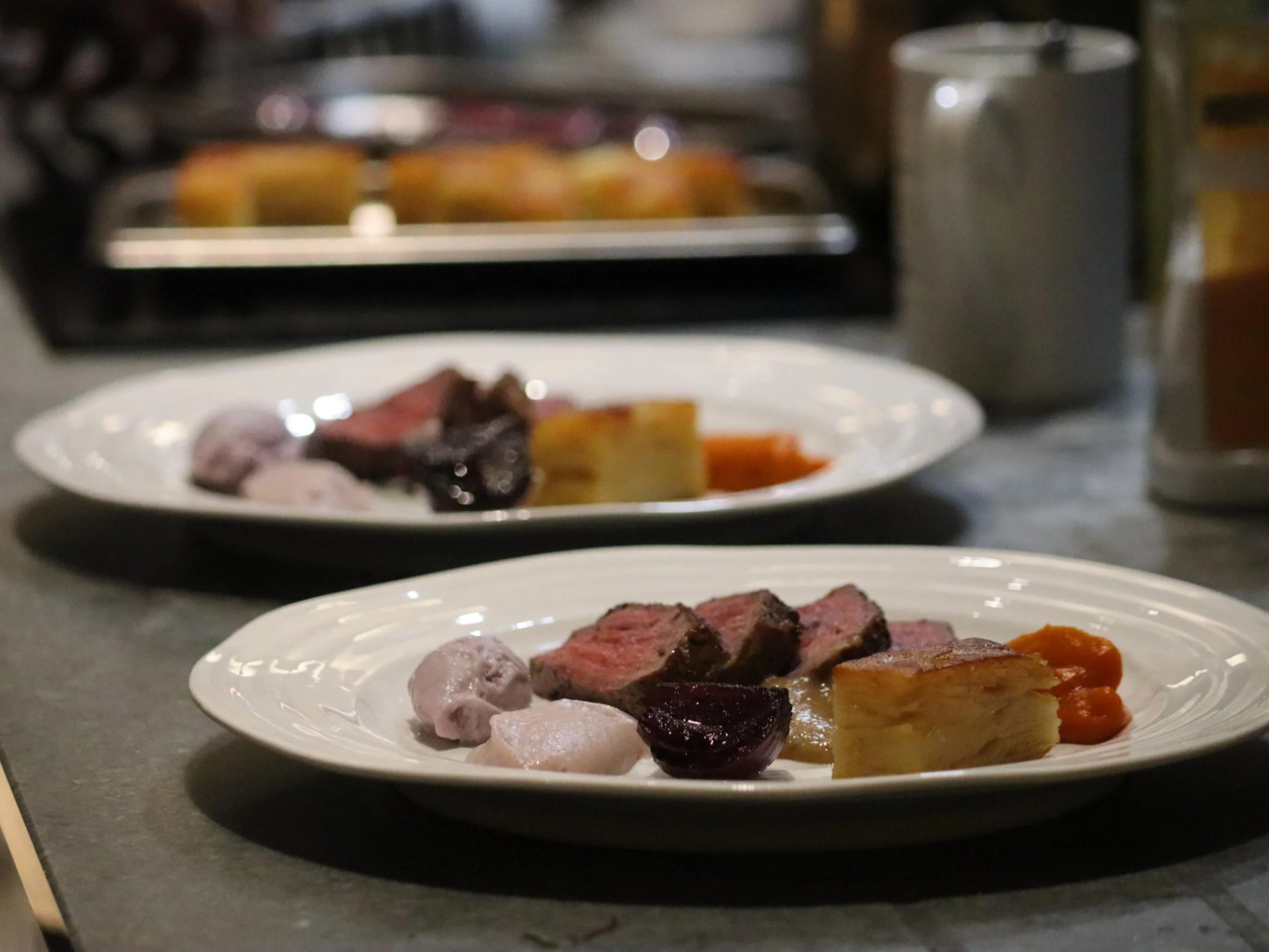 Fine dining roast meat courses with potato terrine and colourful purées ready for service.