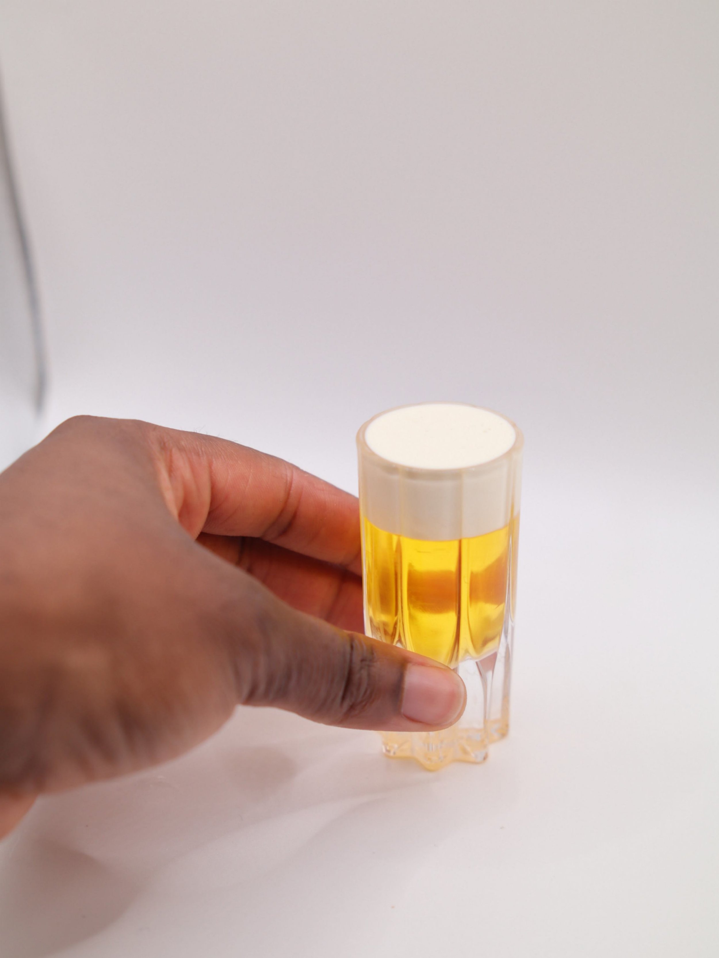 Small golden cocktail shot with a smooth white foam top.
