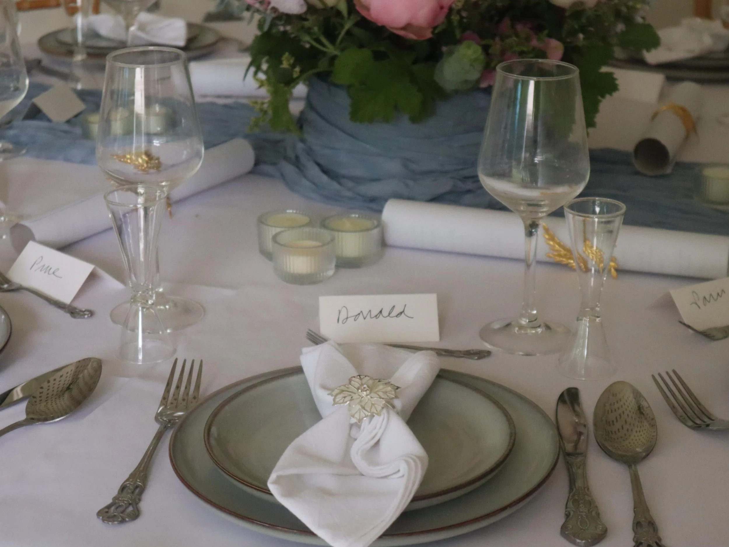 Personalised private dining place setting with grey plates, white napkin and handwritten name card.