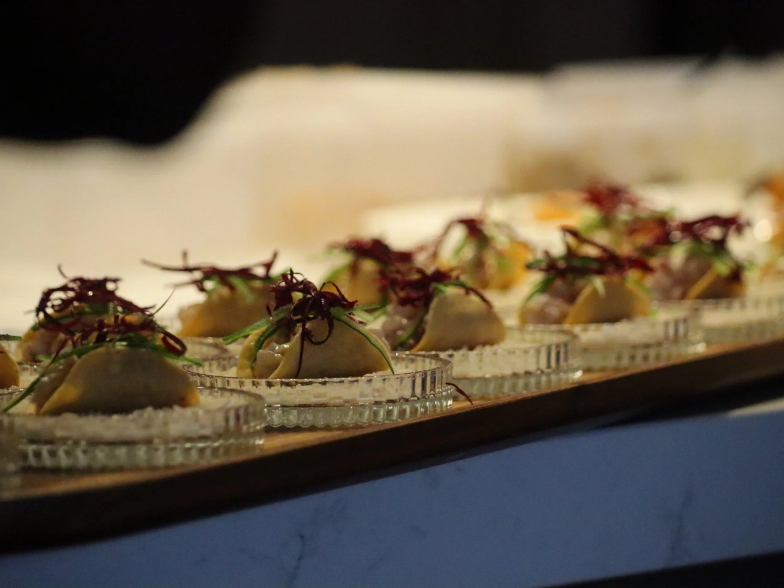 Rows of delicate savoury canapés with creamy filling and colourful micro-herb garnish.