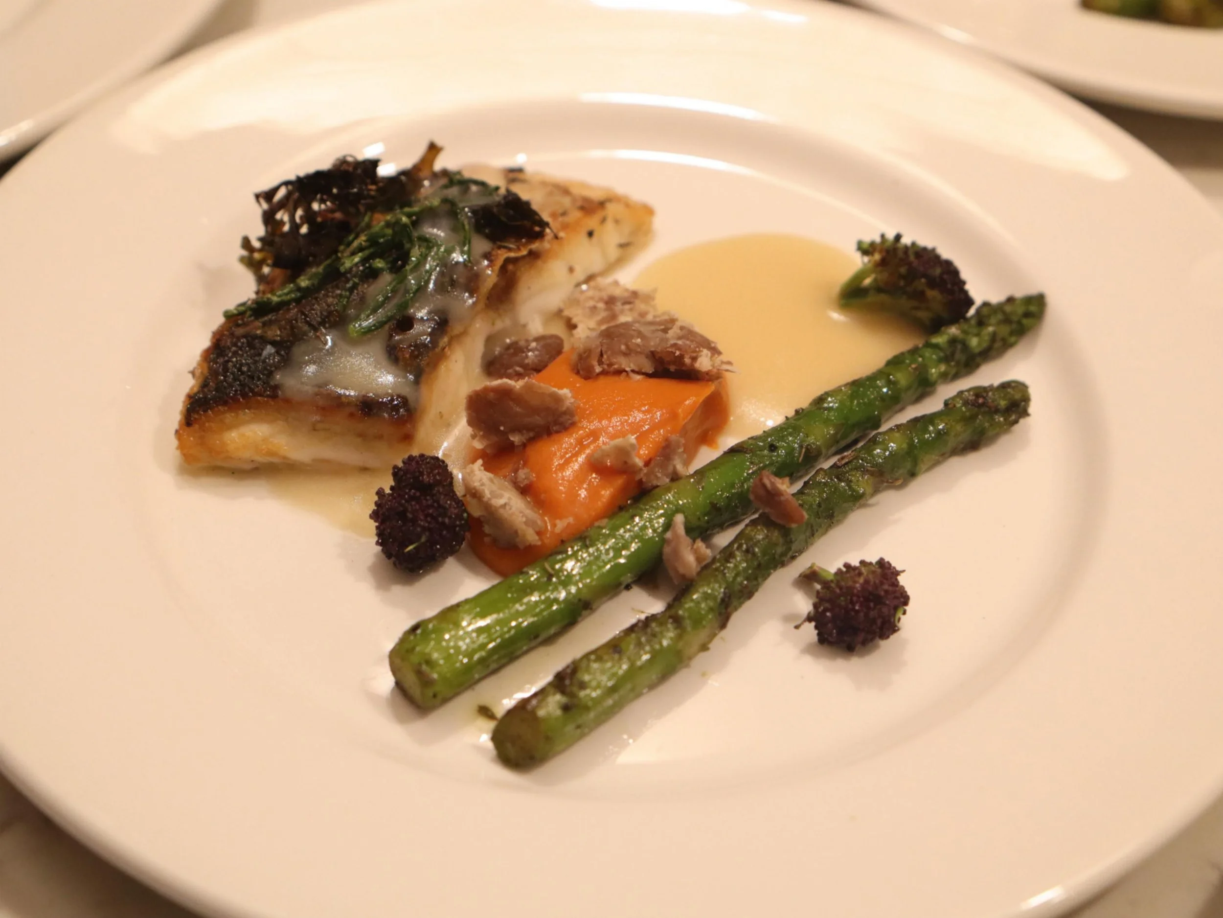 Seared white fish with asparagus, orange purée and seasonal garnish.
