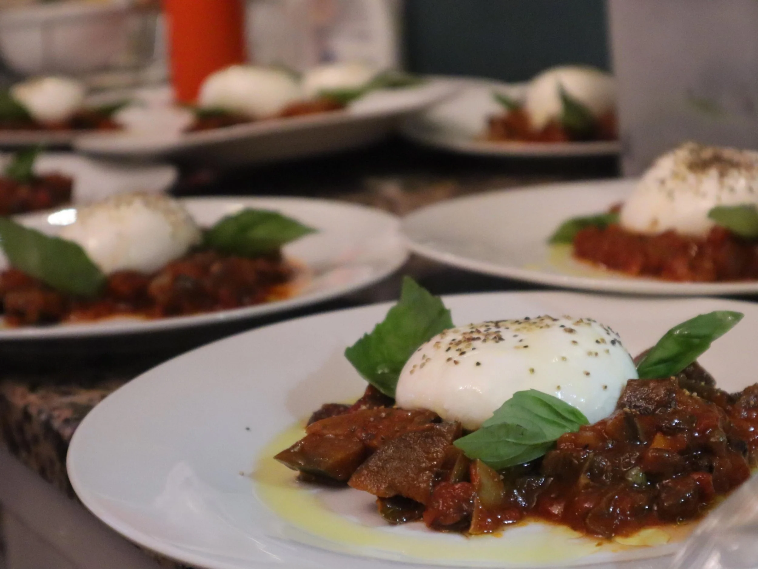 Italian-style aubergine and tomato starter topped with creamy burrata and fresh basil.