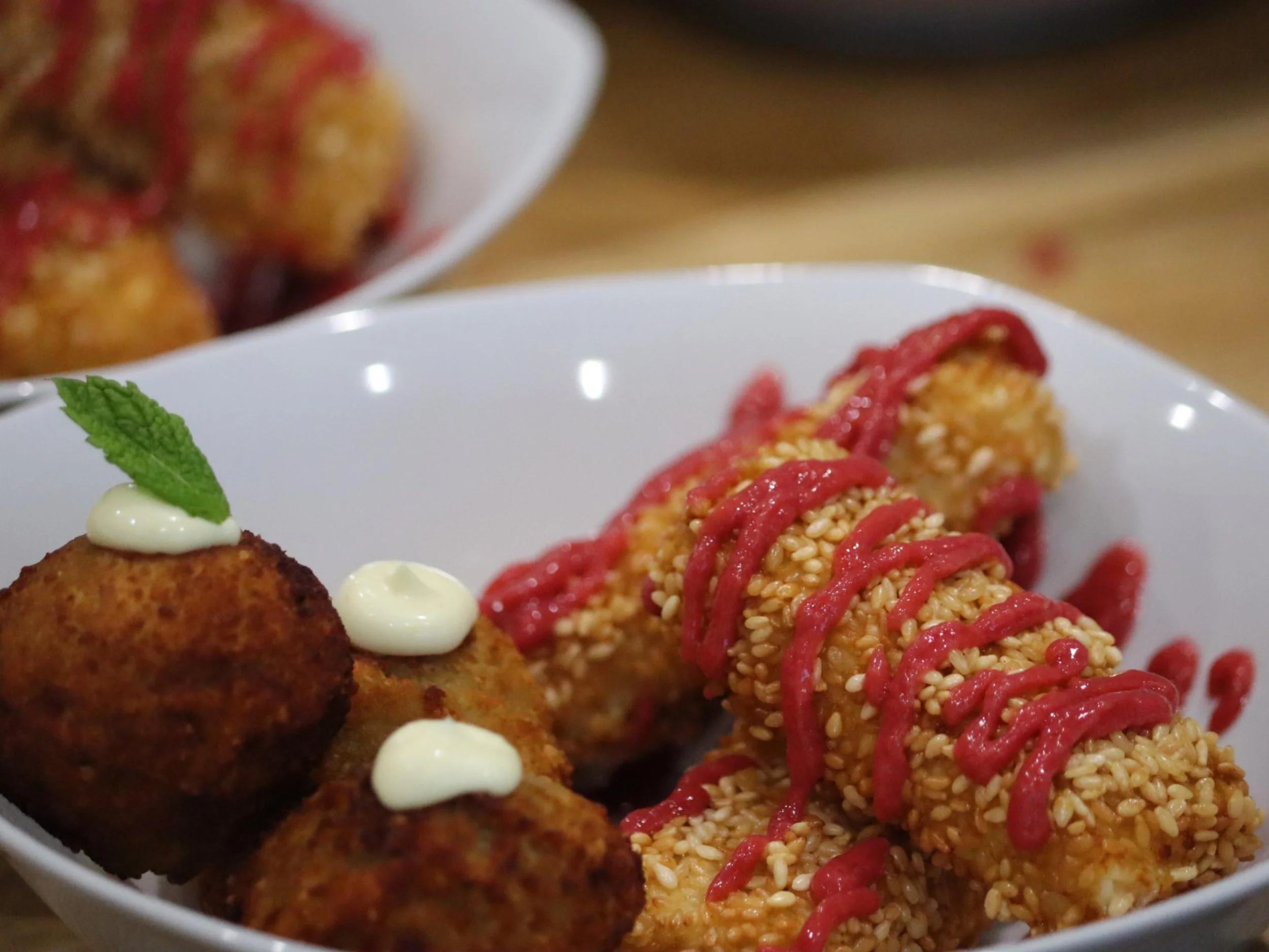 Sesame-crusted feta bites with raspberry sauce alongside golden croquettes and herb mayo.
