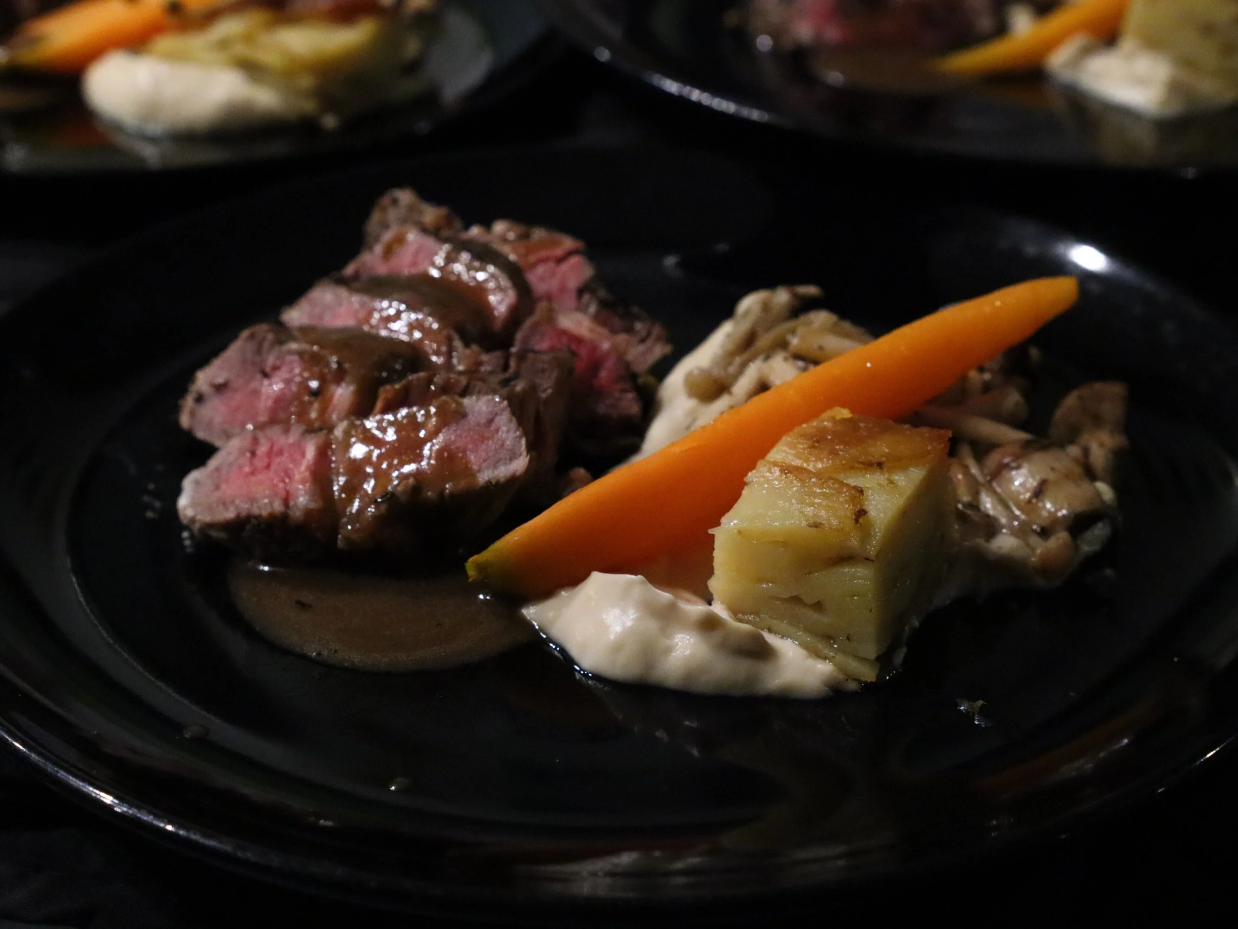 Pink roast meat with dark jus, carrot, mushrooms and layered potato terrine.