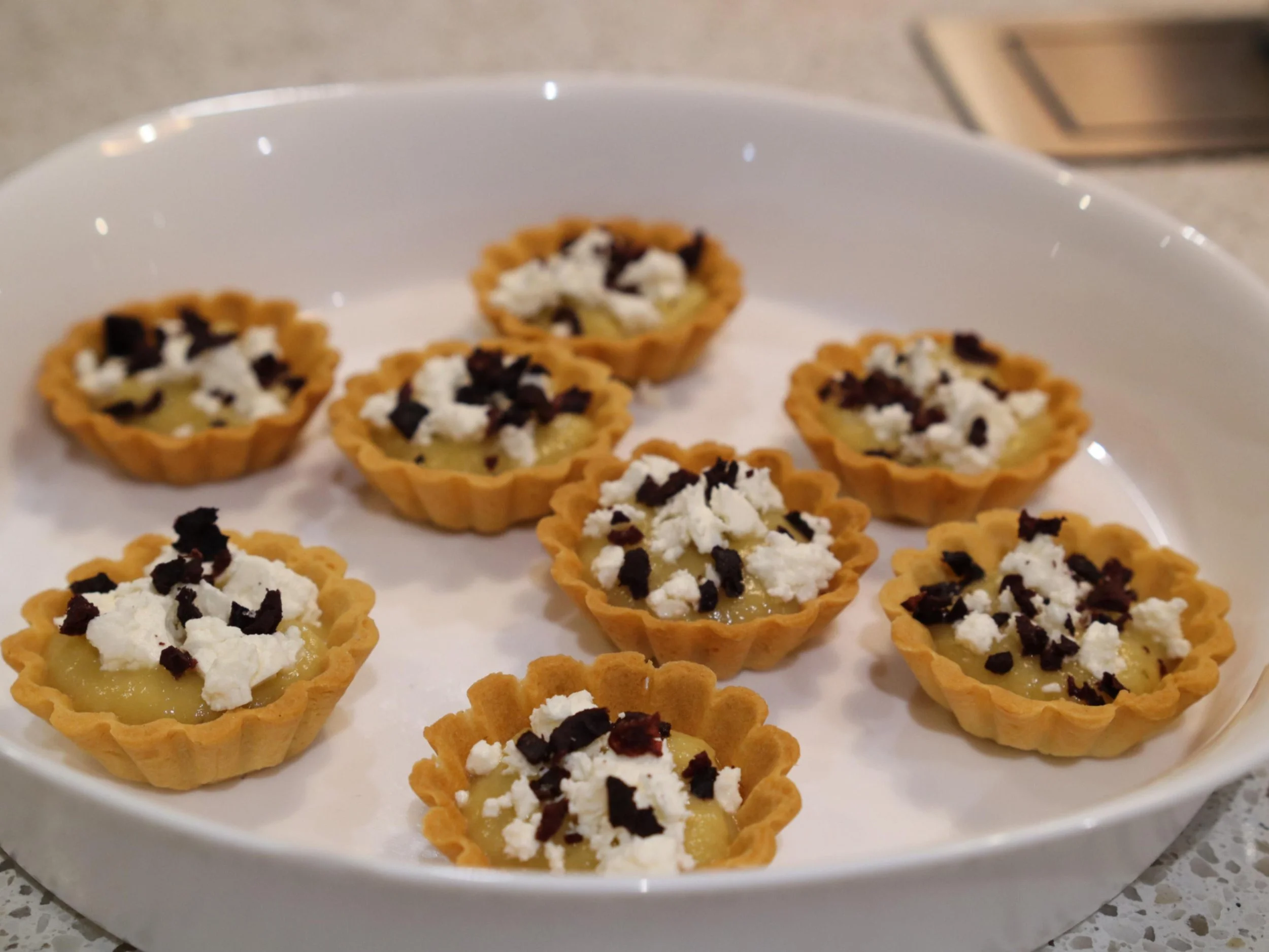 Mini tartlets filled with aubergine dip, feta and dark olive garnish.