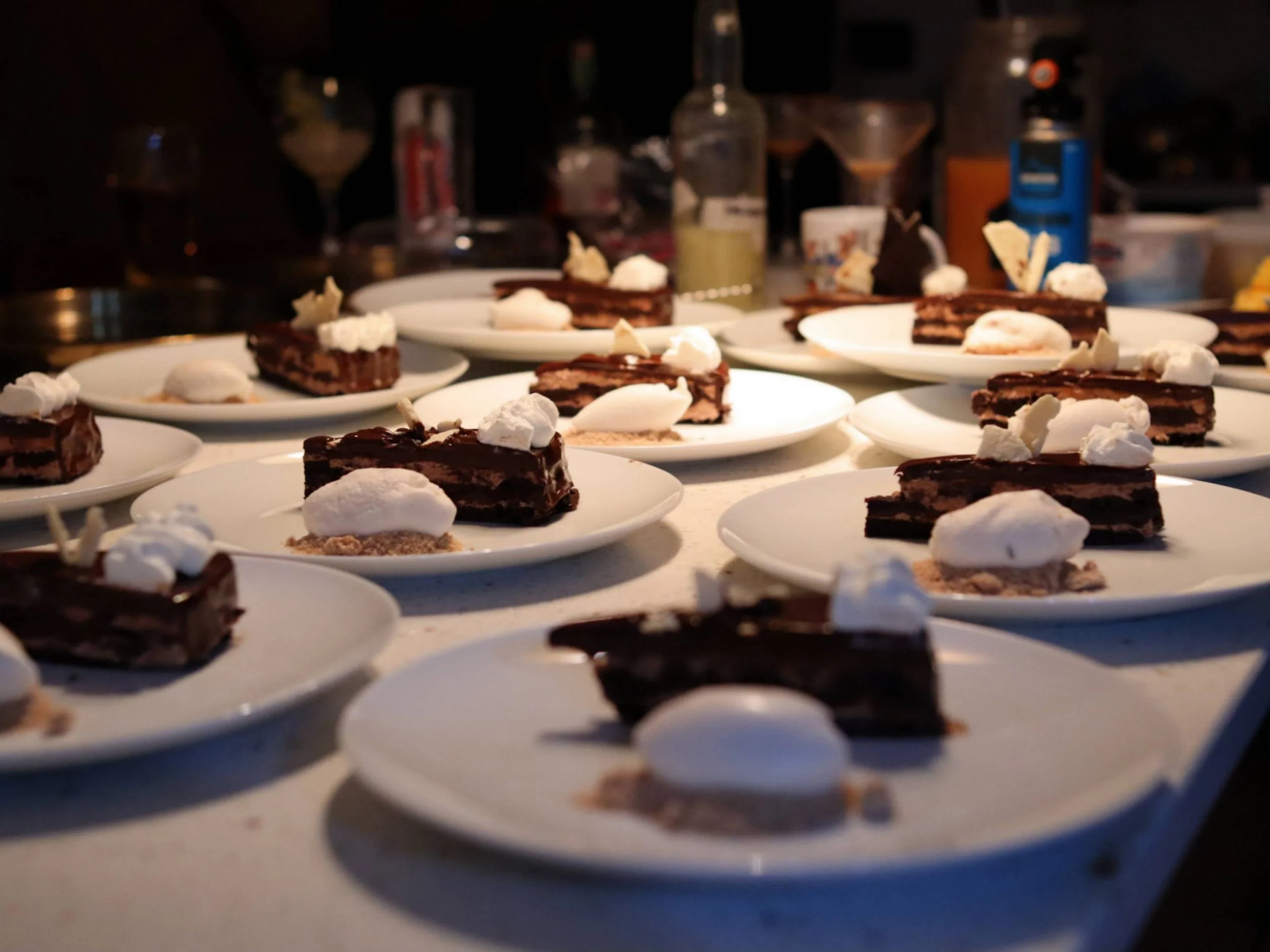  Rows of plated chocolate cake desserts with pale quenelles ready for service.