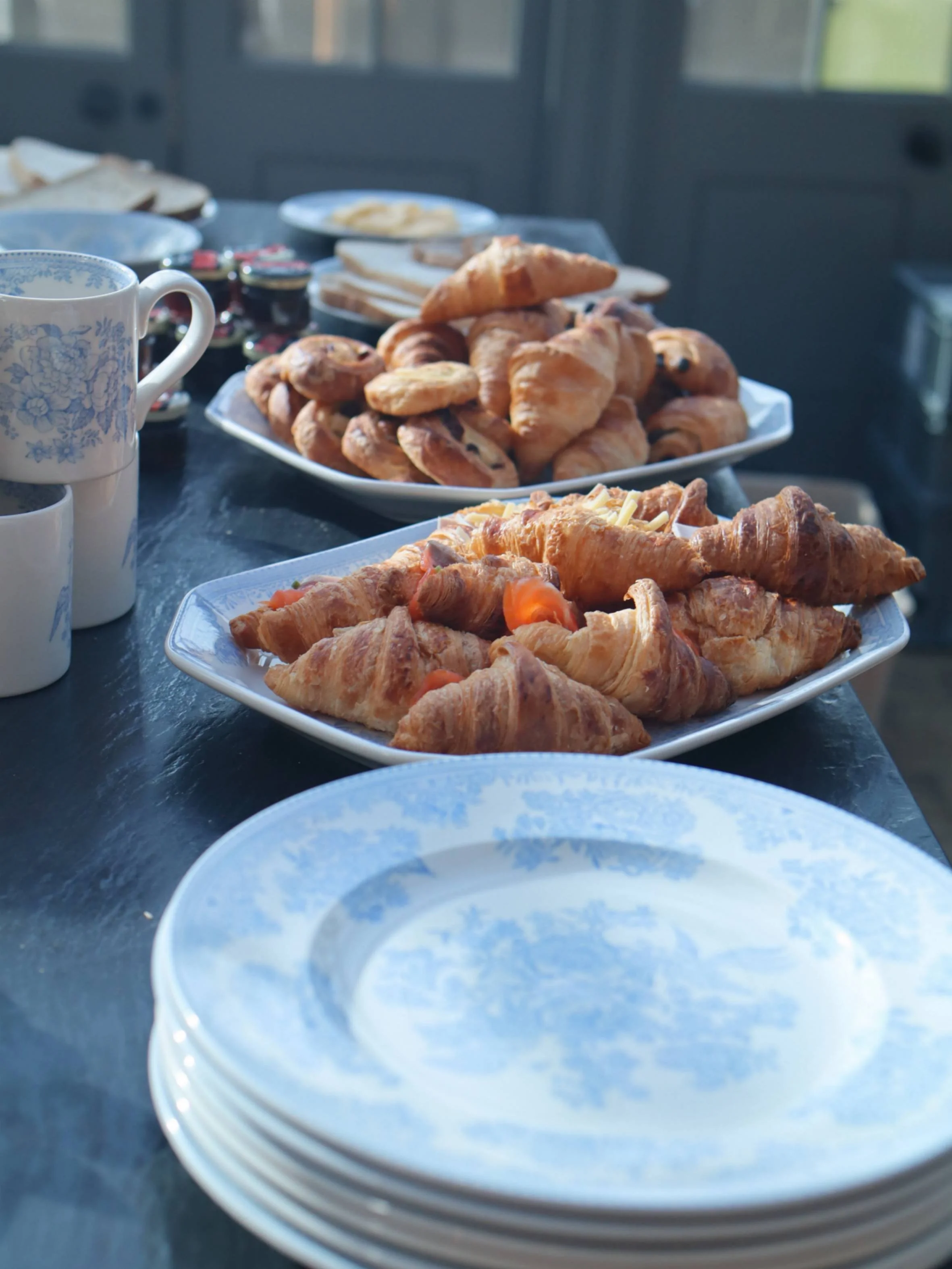 Breakfast spread with croissants, pastries and blue china ready for private dining.
