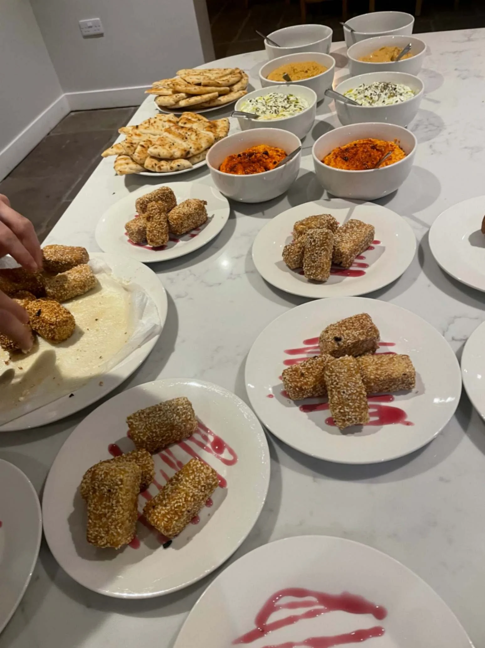 Greek catering spread with pita bread, house-made dips and sesame-crusted feta bites.
