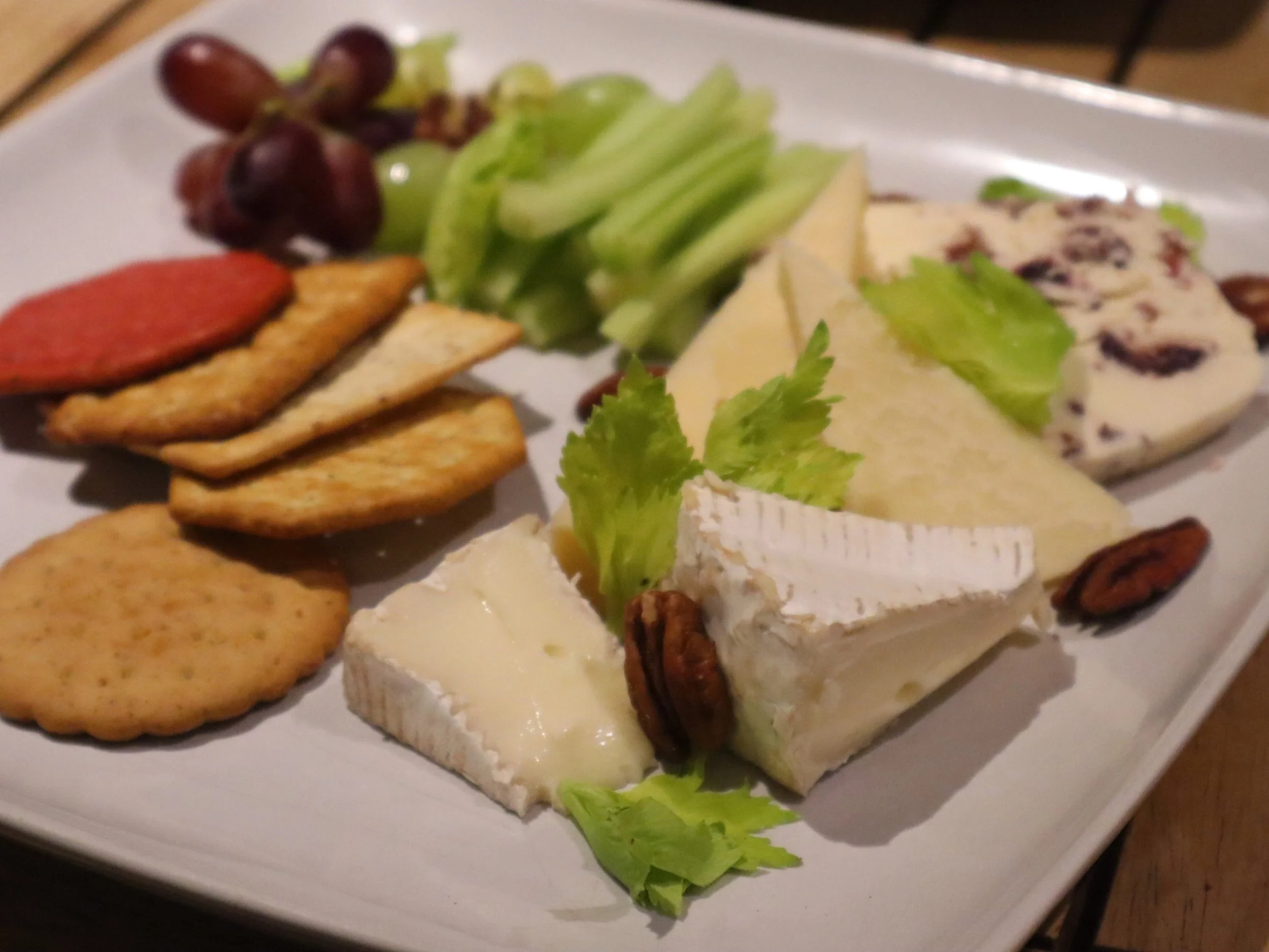 British cheese board with soft and hard cheeses, grapes, celery, crackers and nuts