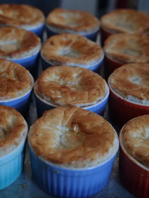 Golden individual puff pastry pies baked in colourful ramekins for private dining service