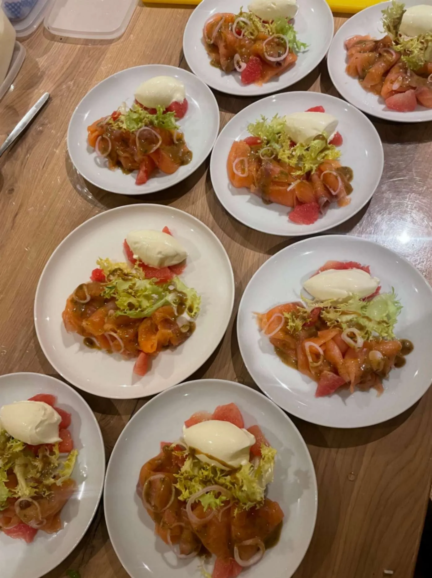 Plated salmon and citrus starters with frisée and a creamy quenelle ready for service.
