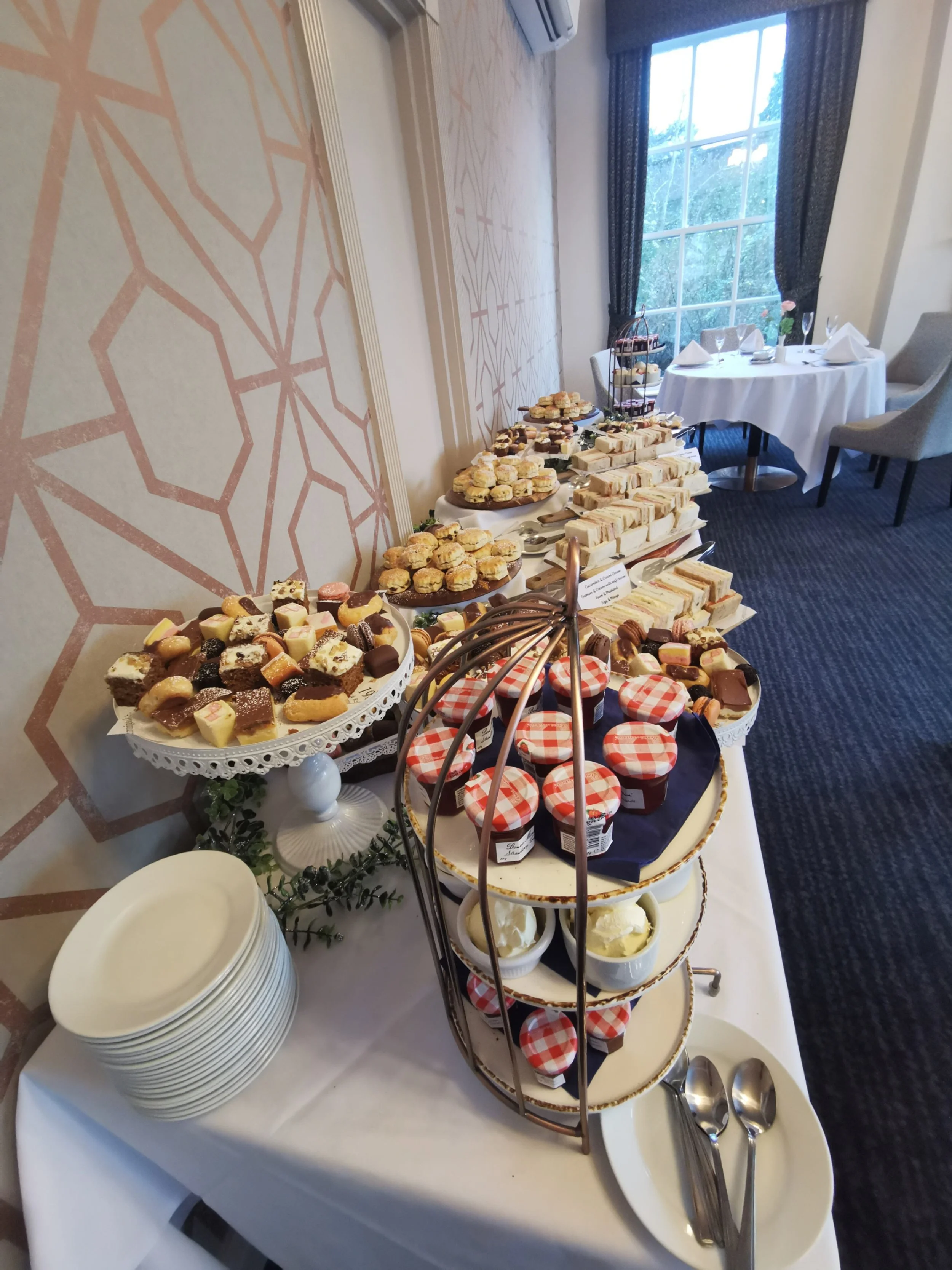 Afternoon tea buffet with finger sandwiches, cakes, pastries, scones and jam for a private event.