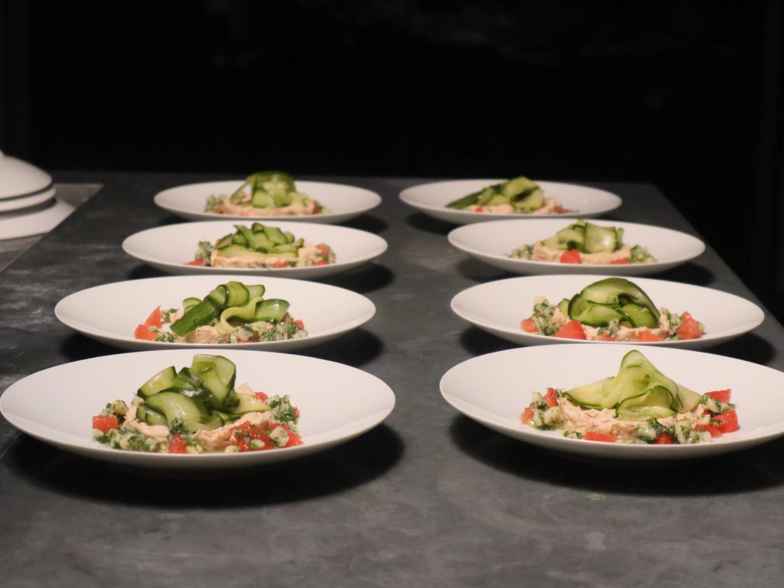 Fresh plated starter with cucumber ribbons, tomato, greens and delicate garnish.
