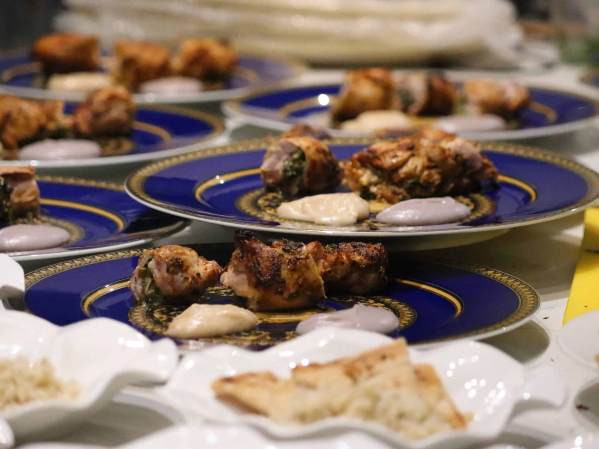 Plated grilled main courses with two smooth purées ready for private dining service.
