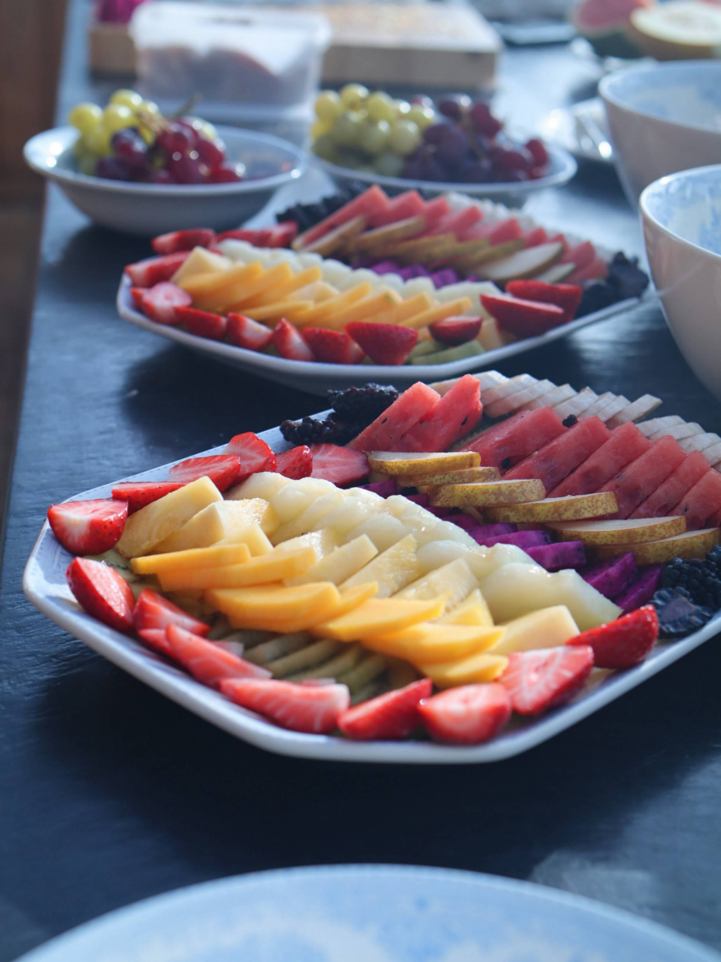 Colourful platters of sliced melon, berries, grapes and other fresh fruit.
