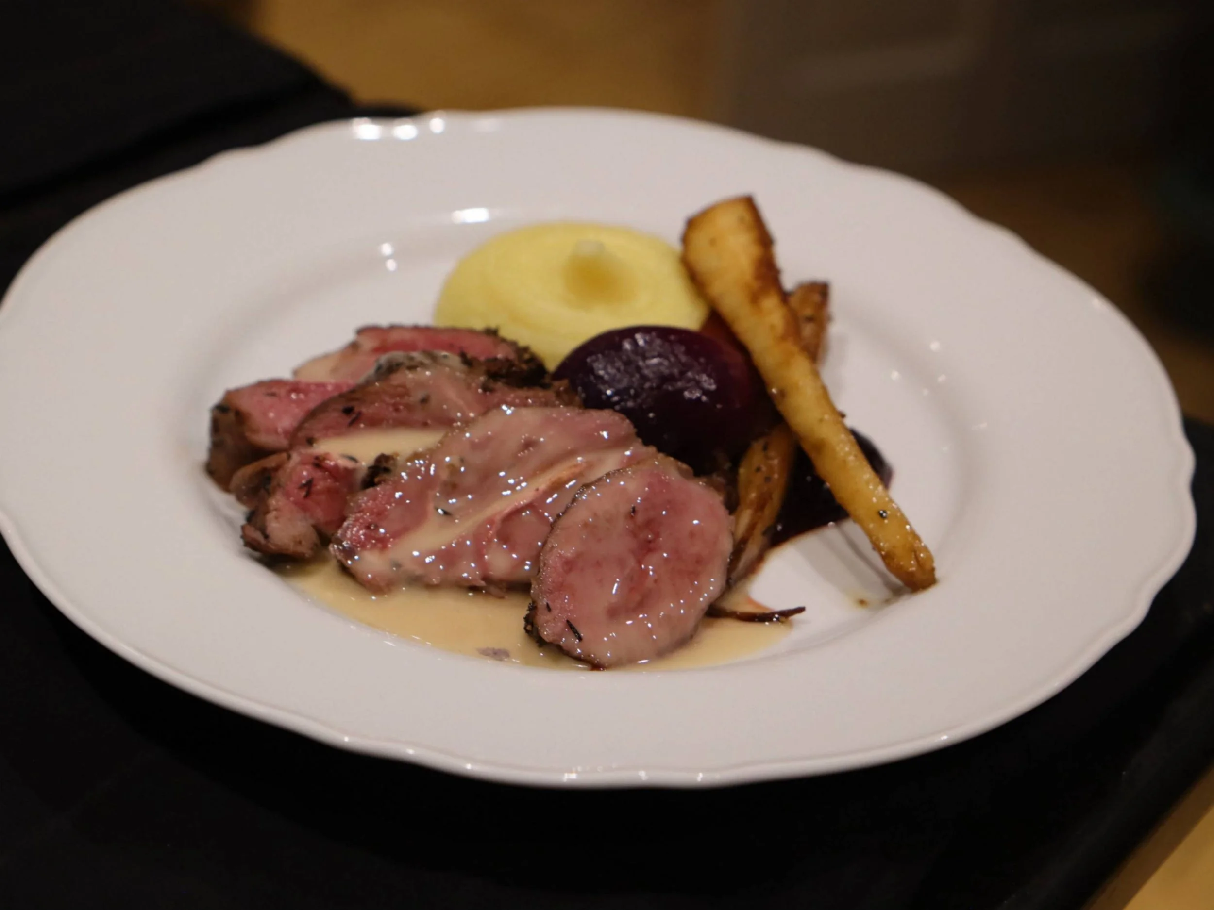 Sliced roast lamb with smooth potato purée, beetroot and roasted root vegetables.
