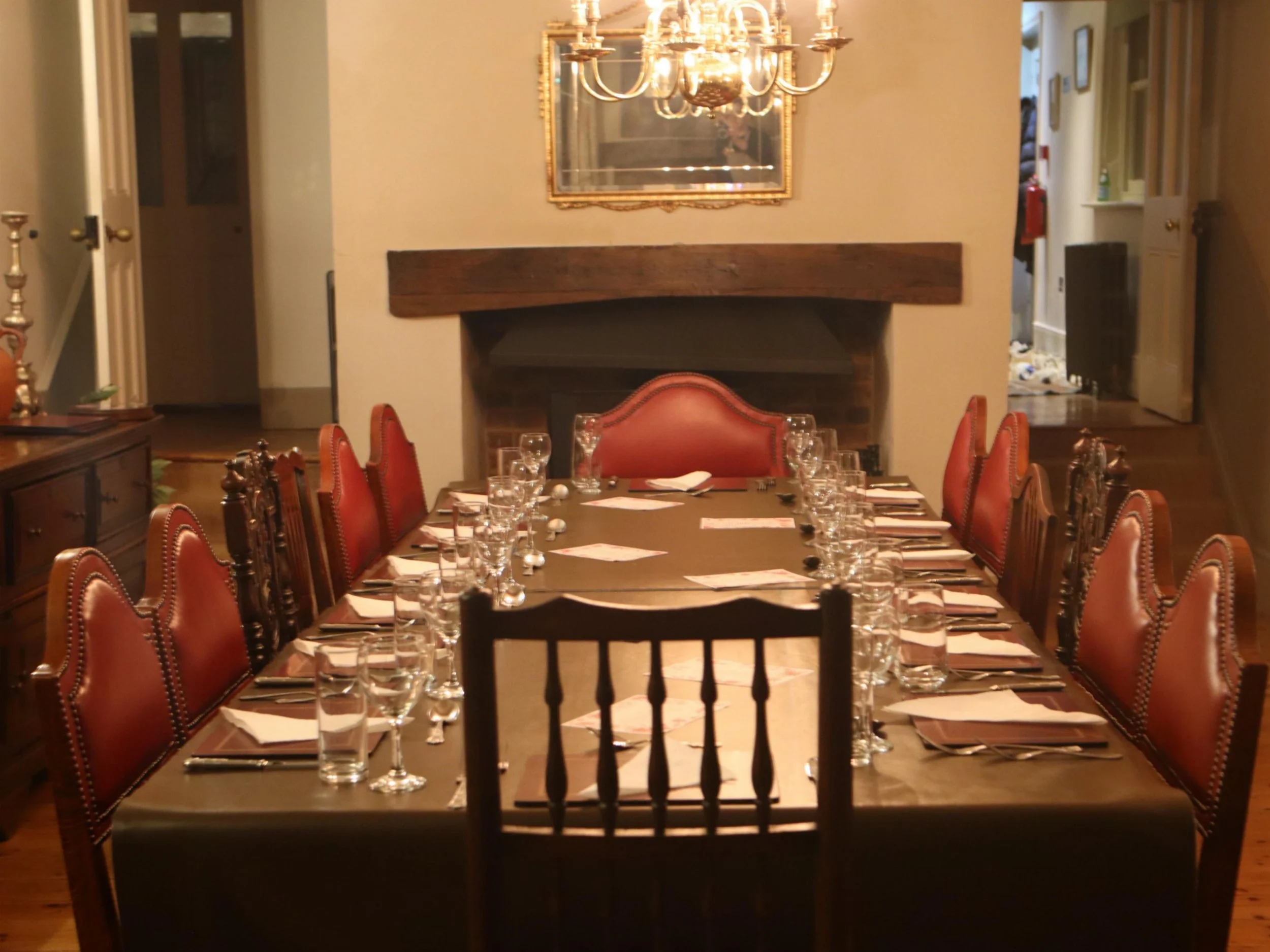 Formal dining table set with glassware, red dining chairs and chandelier in a private venue.
