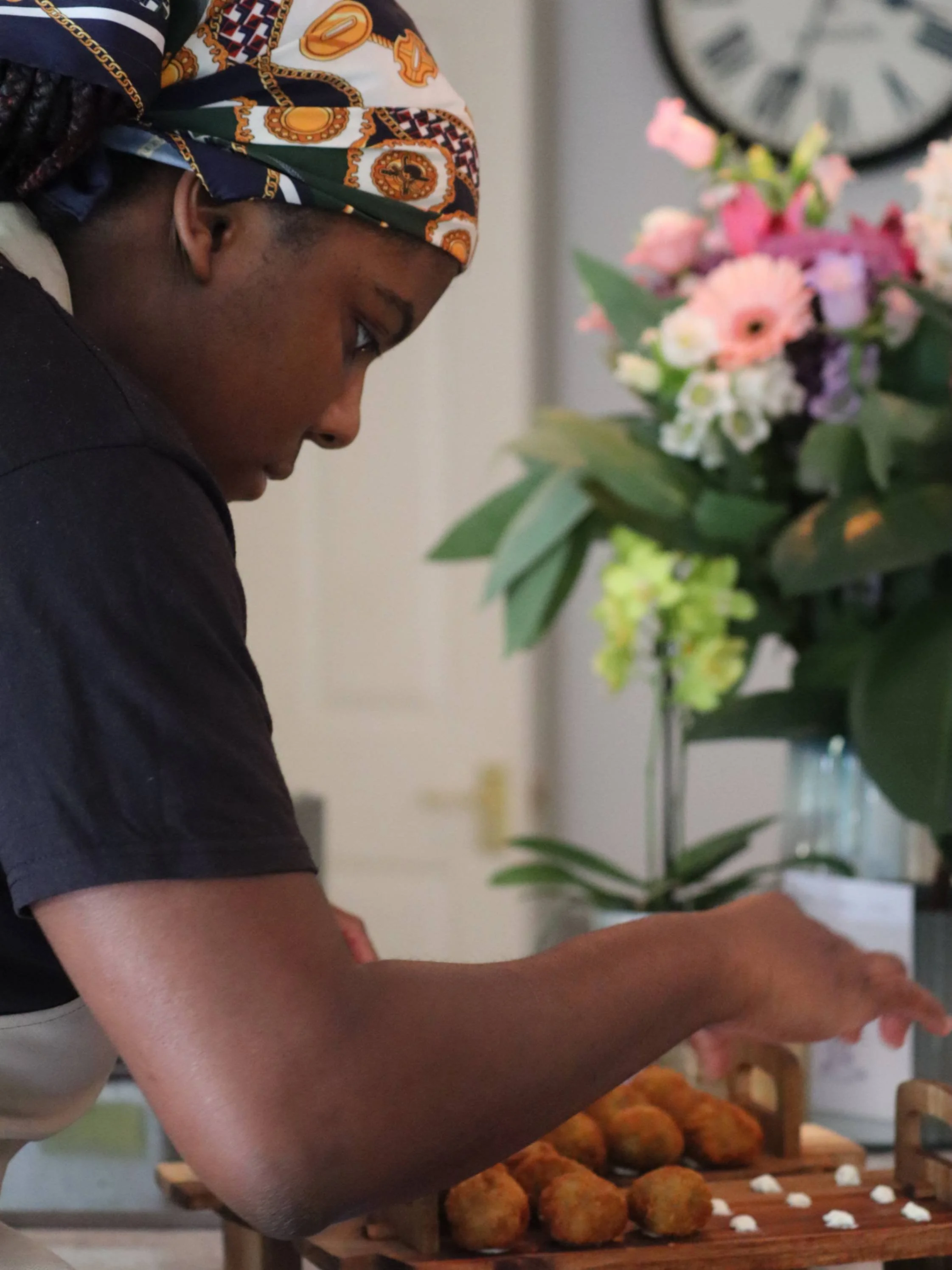 Greek Tings chef arranging croquettes on wooden serving stands before guests arrive.
