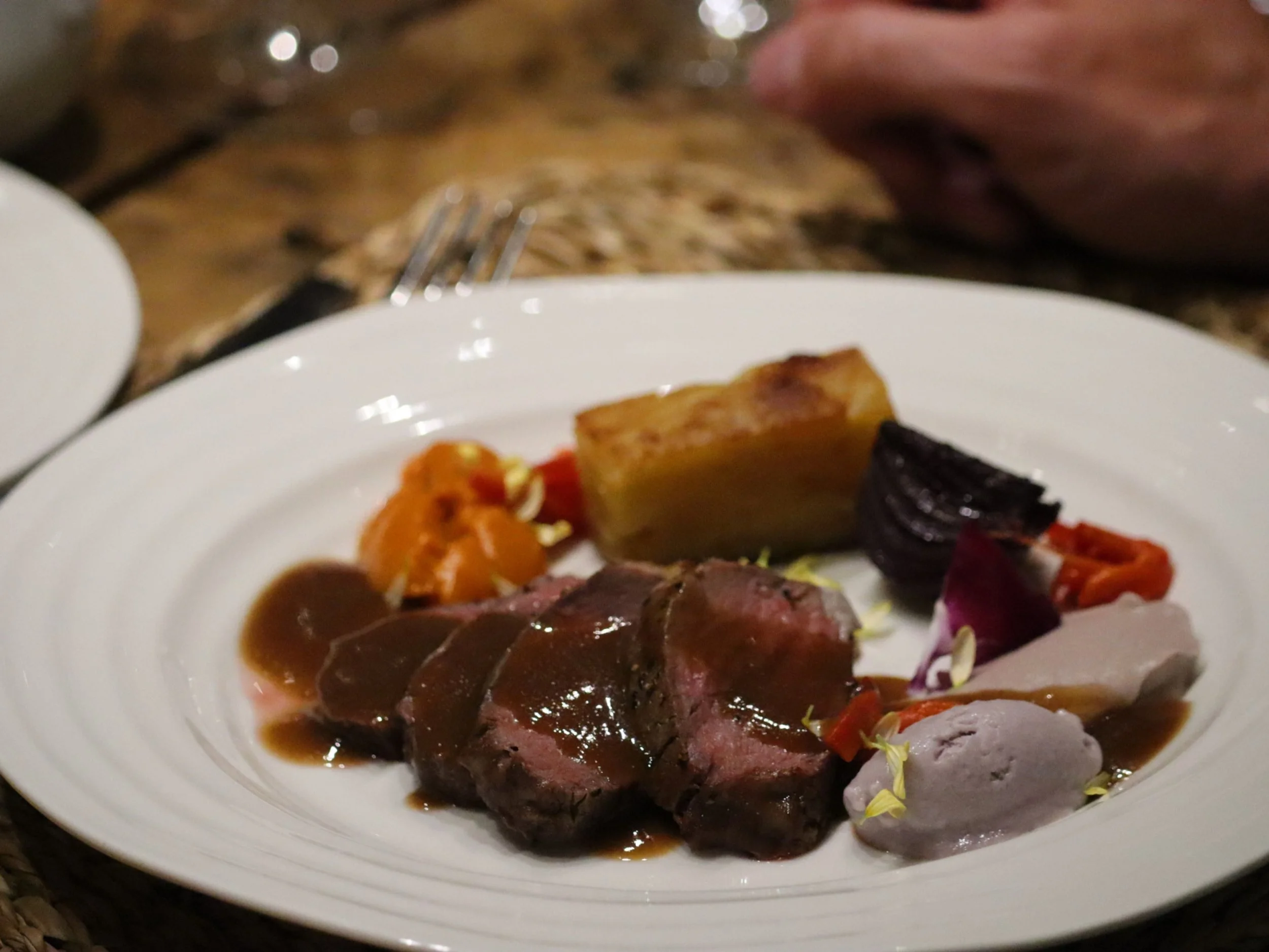 Sliced roast meat with rich jus, potato terrine and colourful purées.