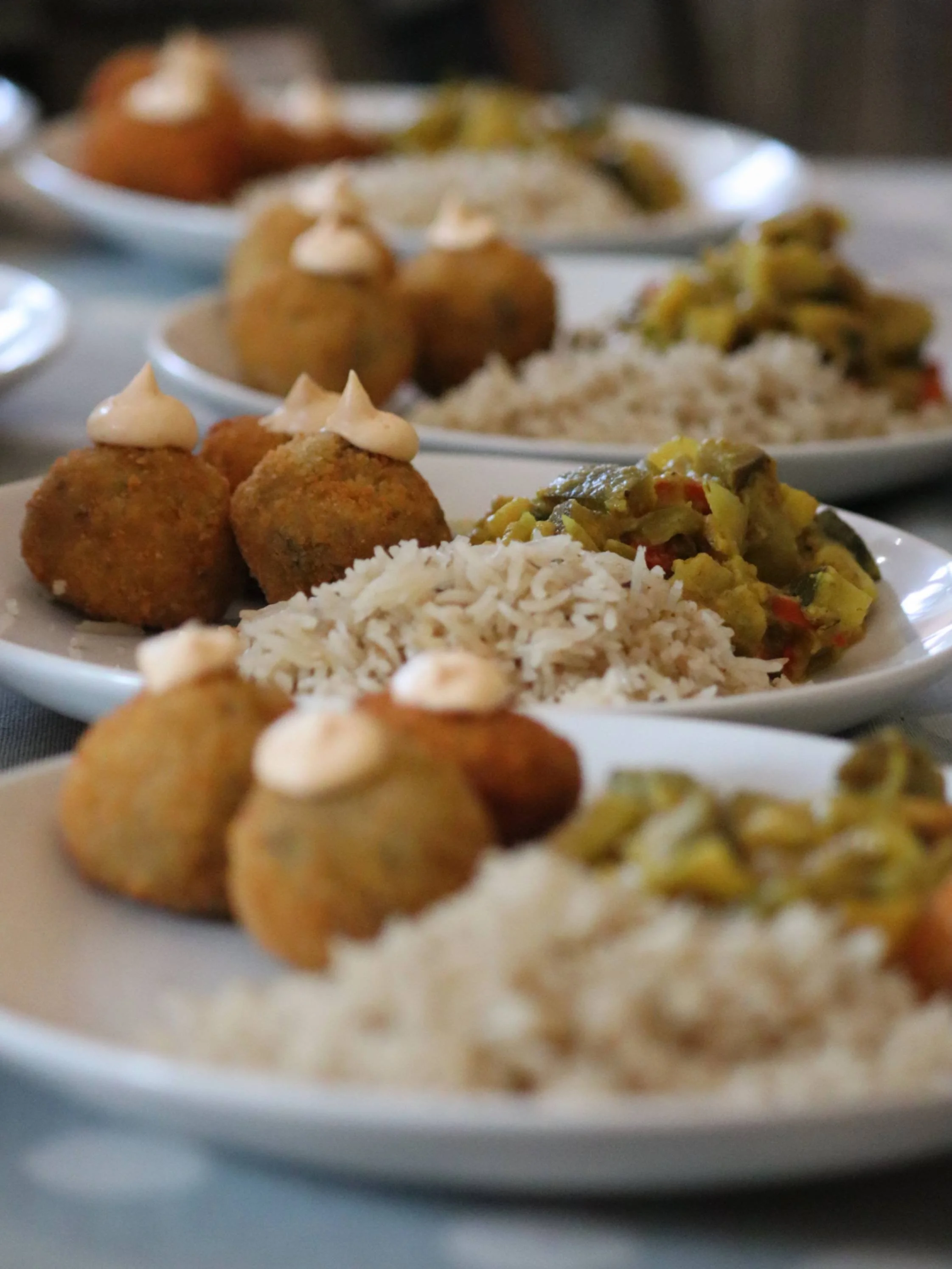  Plates of golden croquettes, herbed rice and vegetables prepared for a Greek Tings event.