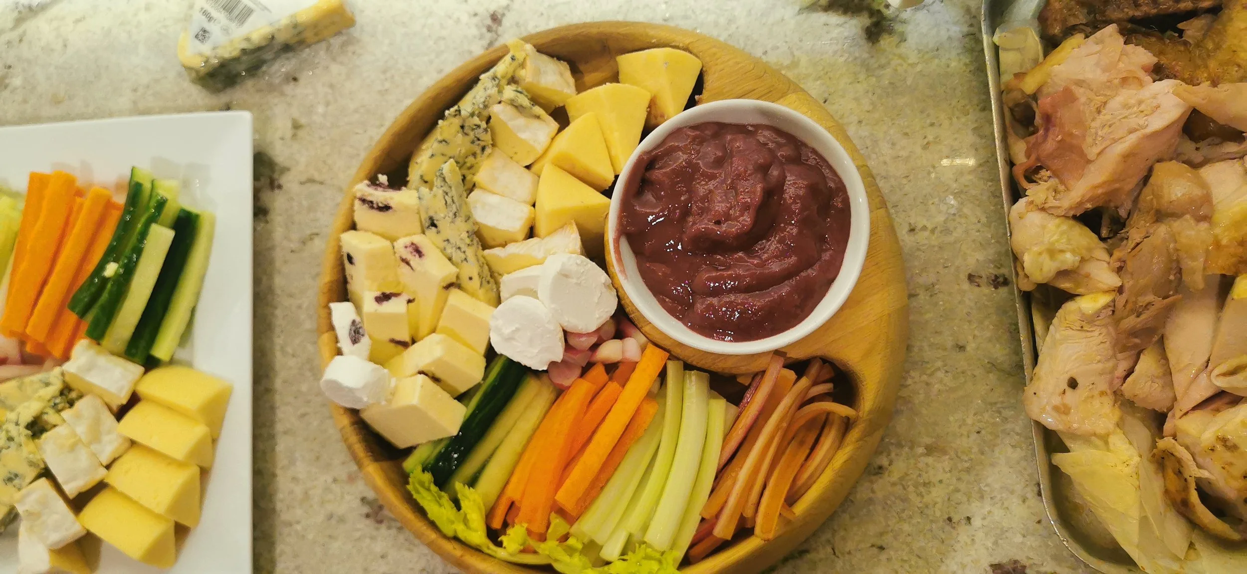 Christmas sharing platter with British cheeses, vegetable crudités and a bowl of red chutney.