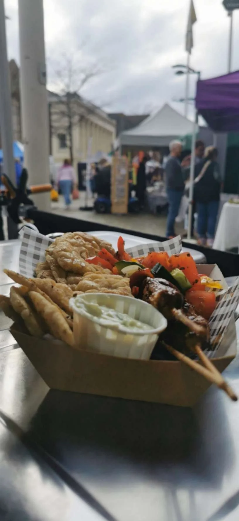 Festival street food box with grilled skewers, vegetables, fried bites and creamy dip.