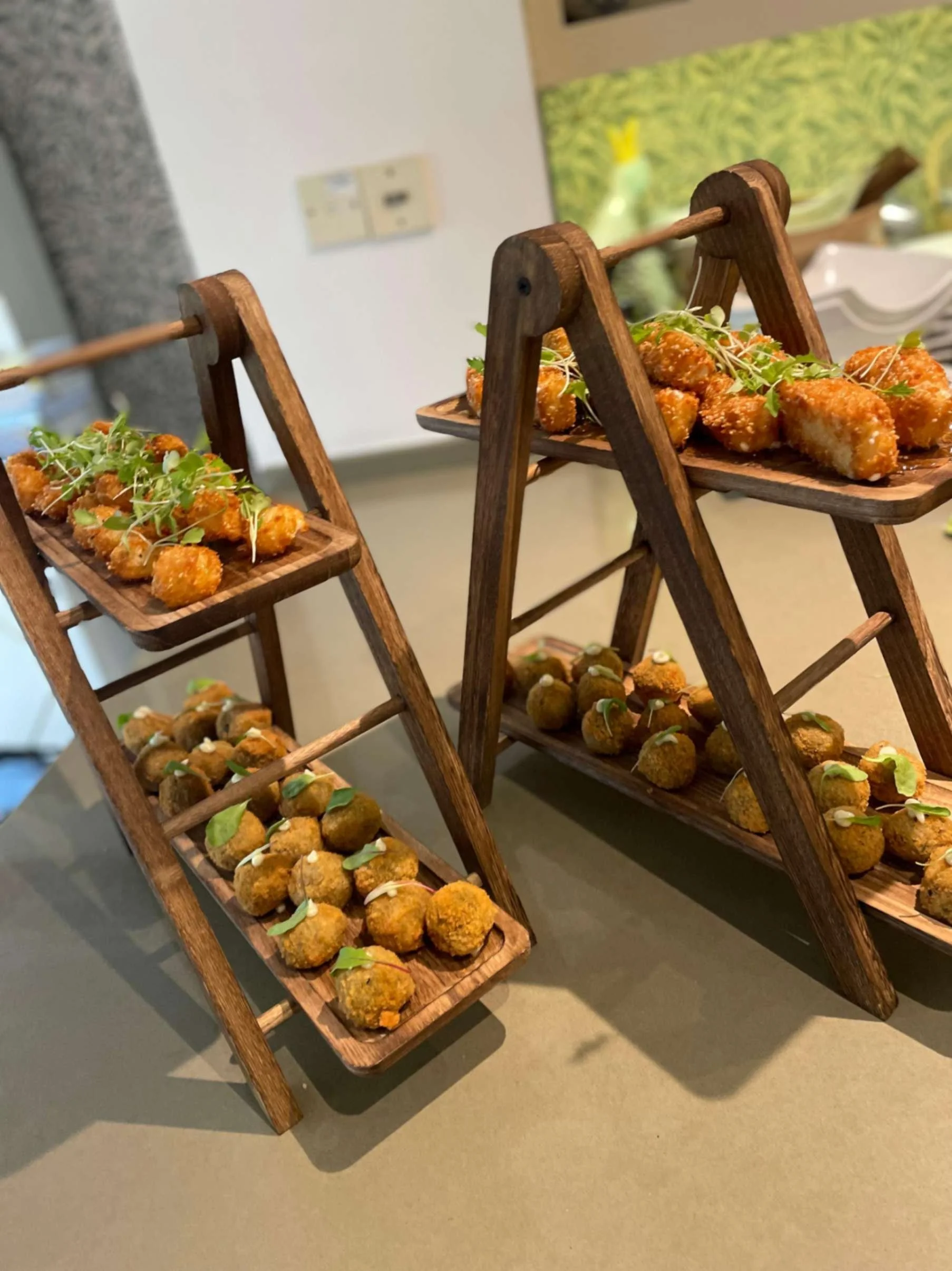 Wooden canapé stands filled with golden savoury bites and sesame-crusted feta at a Greek Tings event.