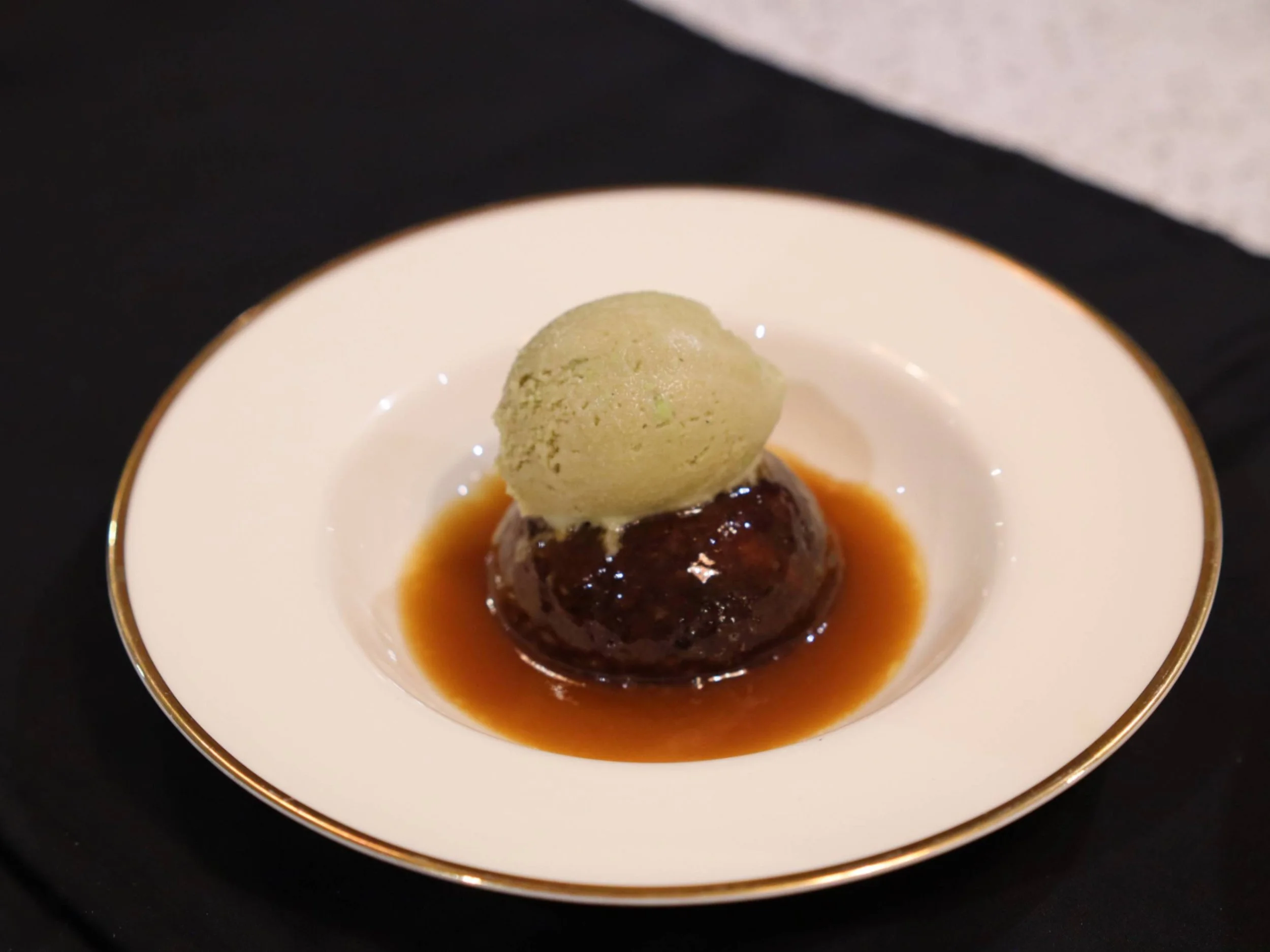 Warm sticky toffee-style pudding with caramel sauce and a scoop of ice cream.
