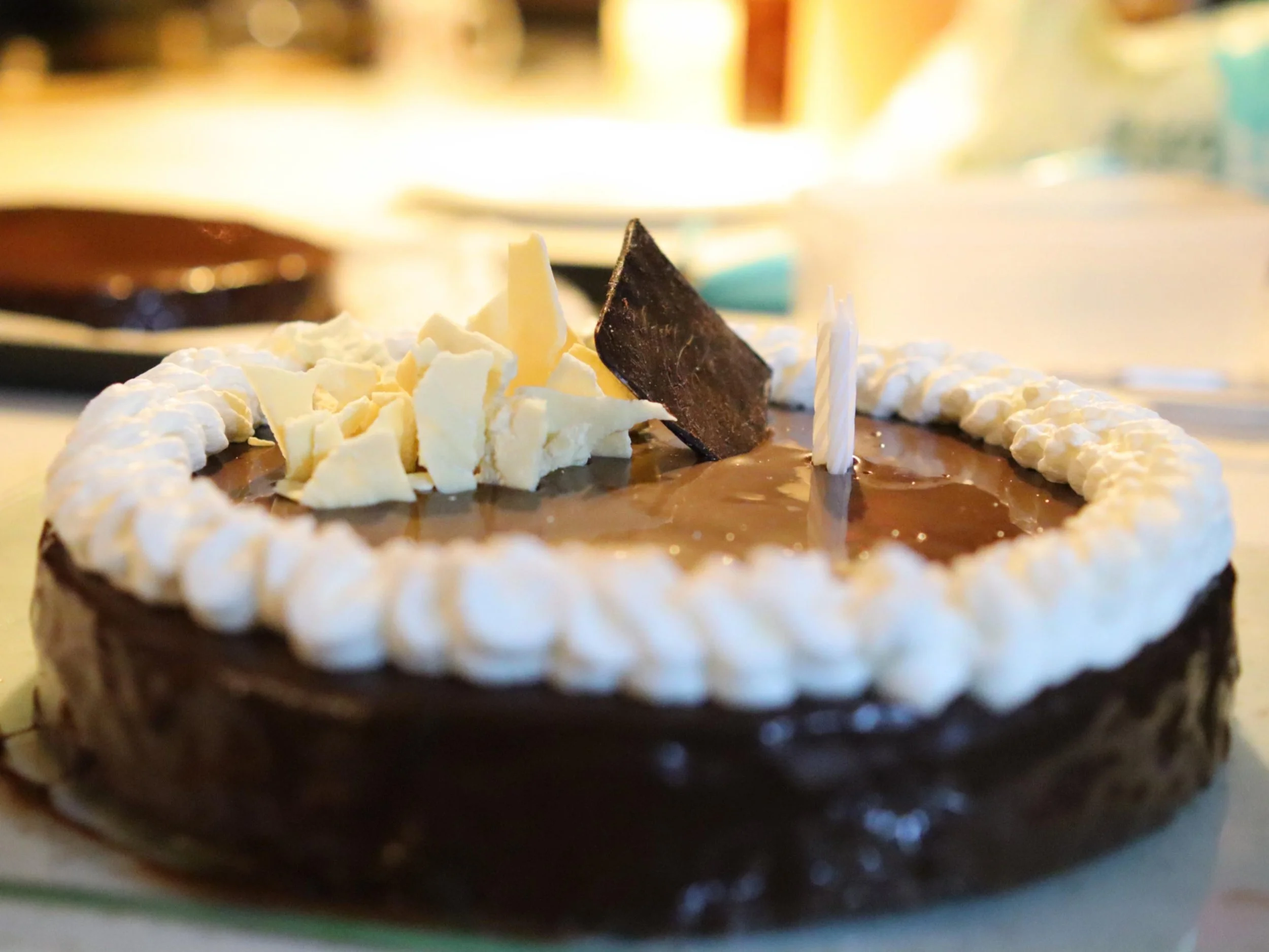  Glossy chocolate celebration cake finished with whipped cream and chocolate shards.