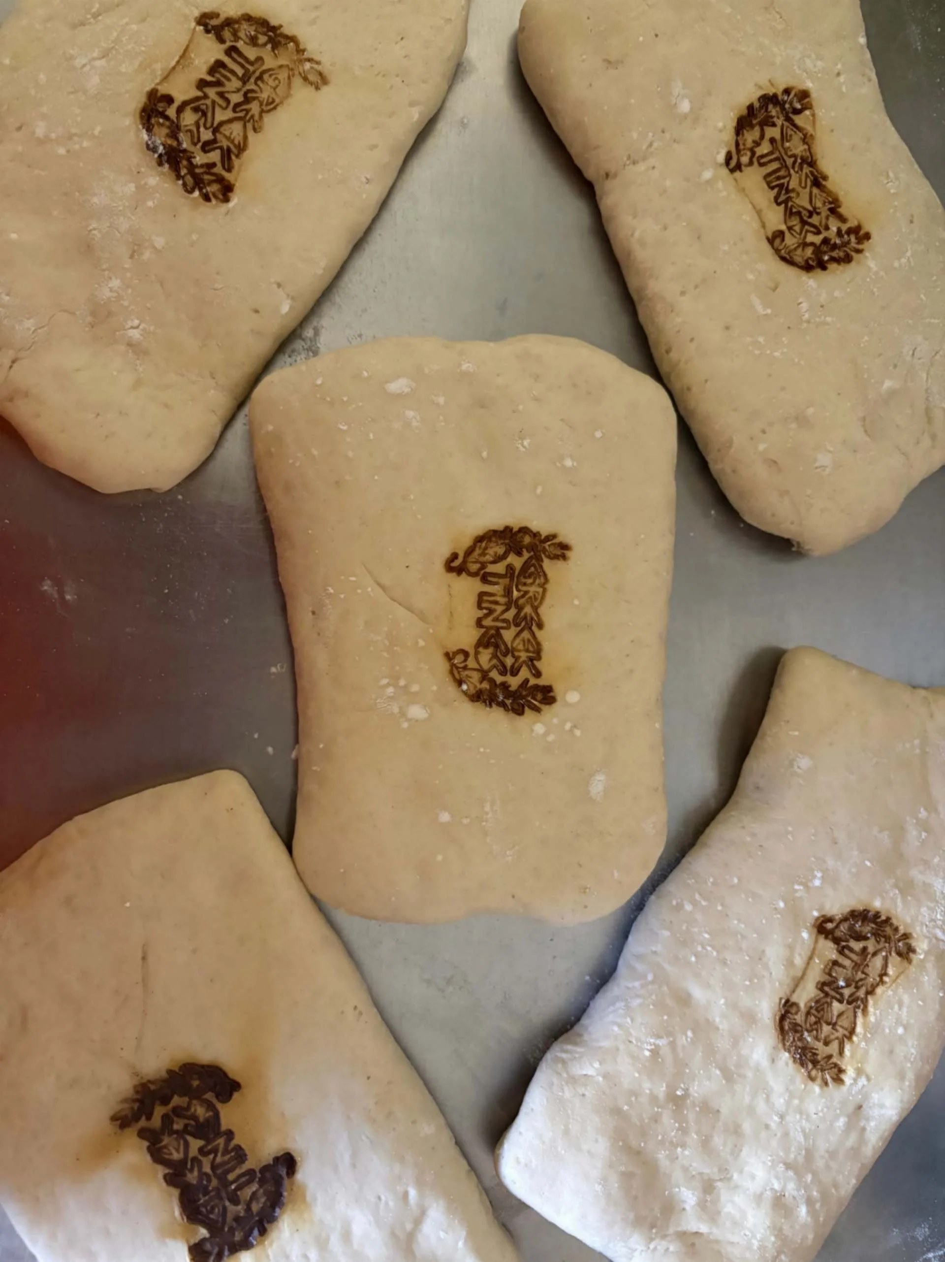Handmade pastry portions stamped with the Greek Tings logo before baking.
