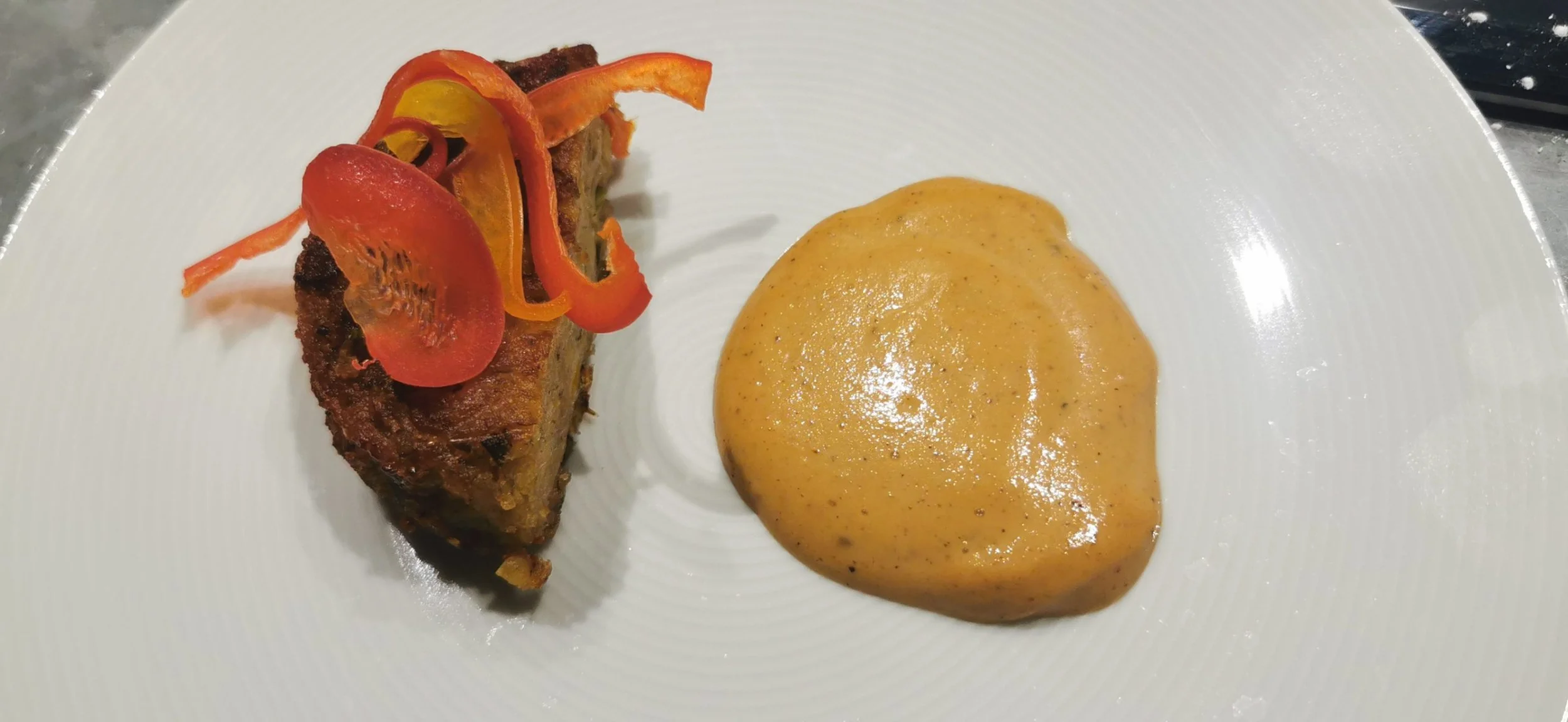 Jamaican ackee and saltfish fritter served with plantain foam and sweet pepper garnish, plated for Greek Tings fine dining.