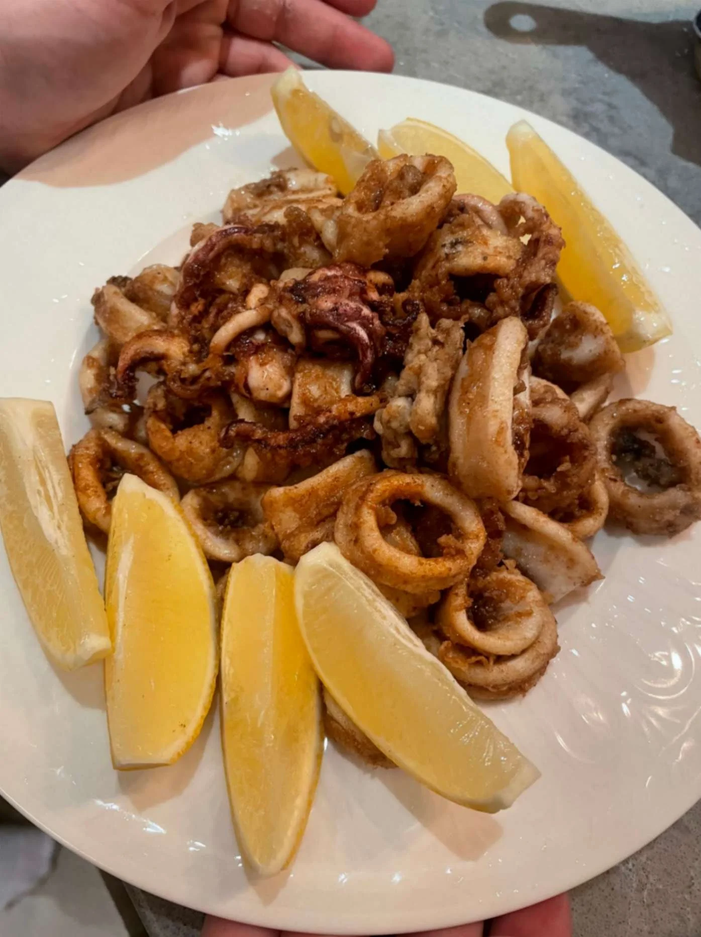 Plate of crisp fried calamari served with fresh lemon wedges.
