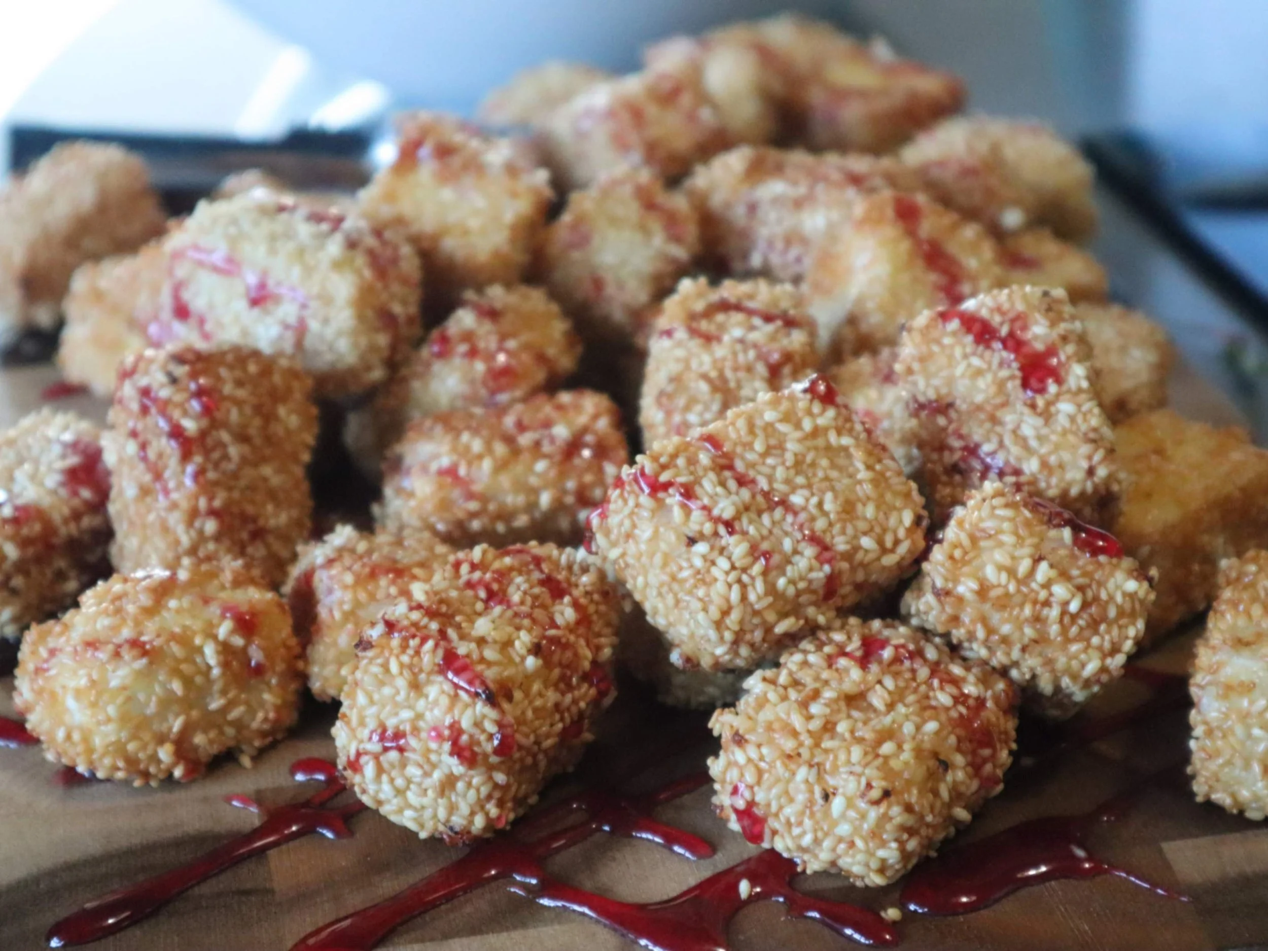 Sesame-crusted feta bites drizzled with Greek honey and served with raspberry sauce.