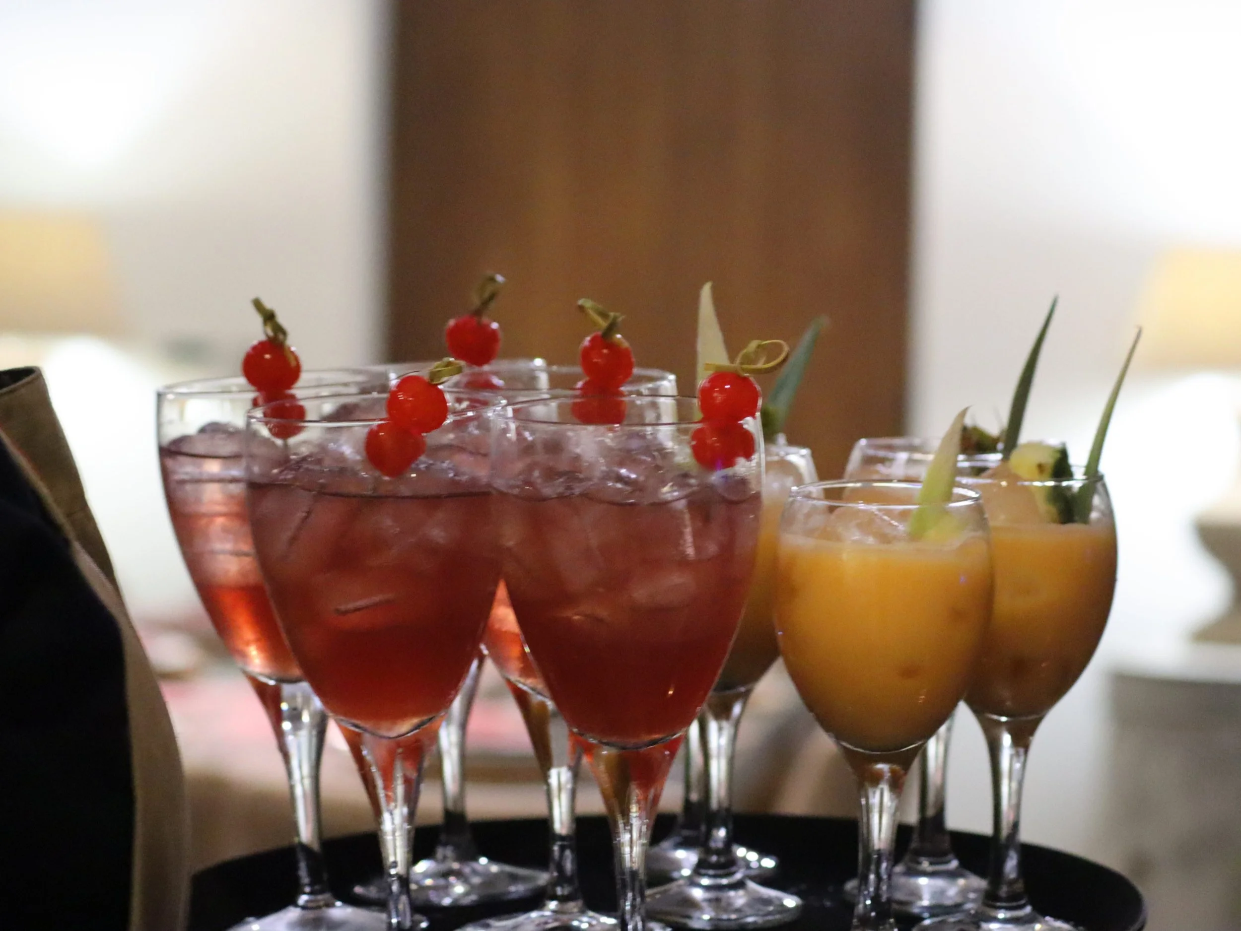 Red cocktail with cherry garnish, Boozy Bakewell, cherry Bakewell inspired cocktail, tropical margarita, passionfruit tequila creme, fresh pineapple juice, infused sugar syrup, cinnamon, cloves, garnished with pineapple triangle and pineapple leaf