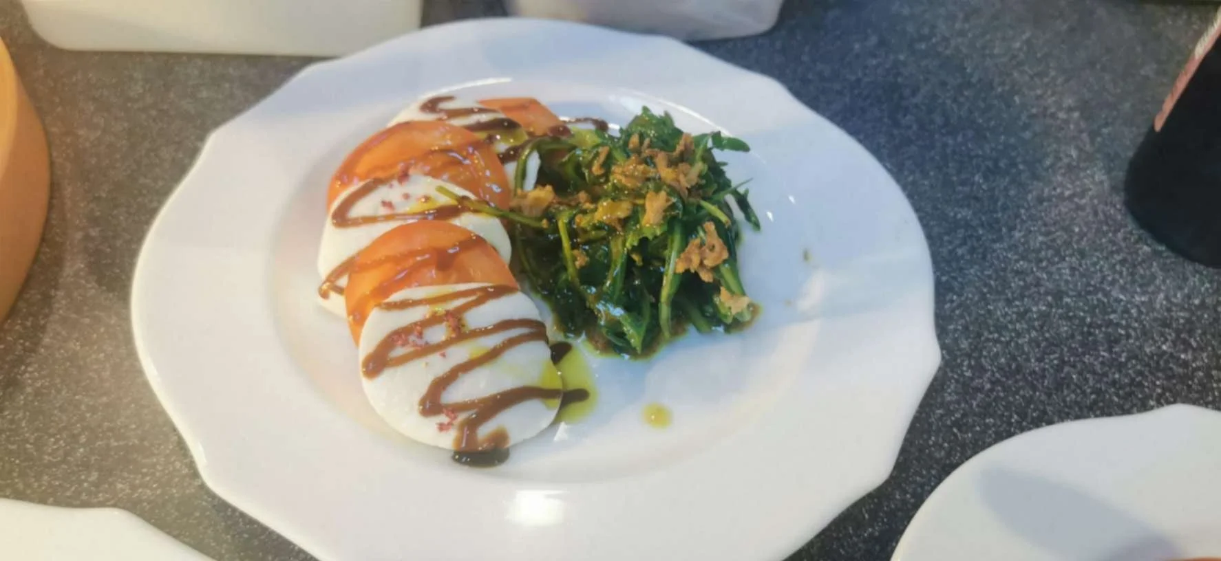 Tomato and Mozzarella starter with dressed greens, olive oil and balsamic glaze.