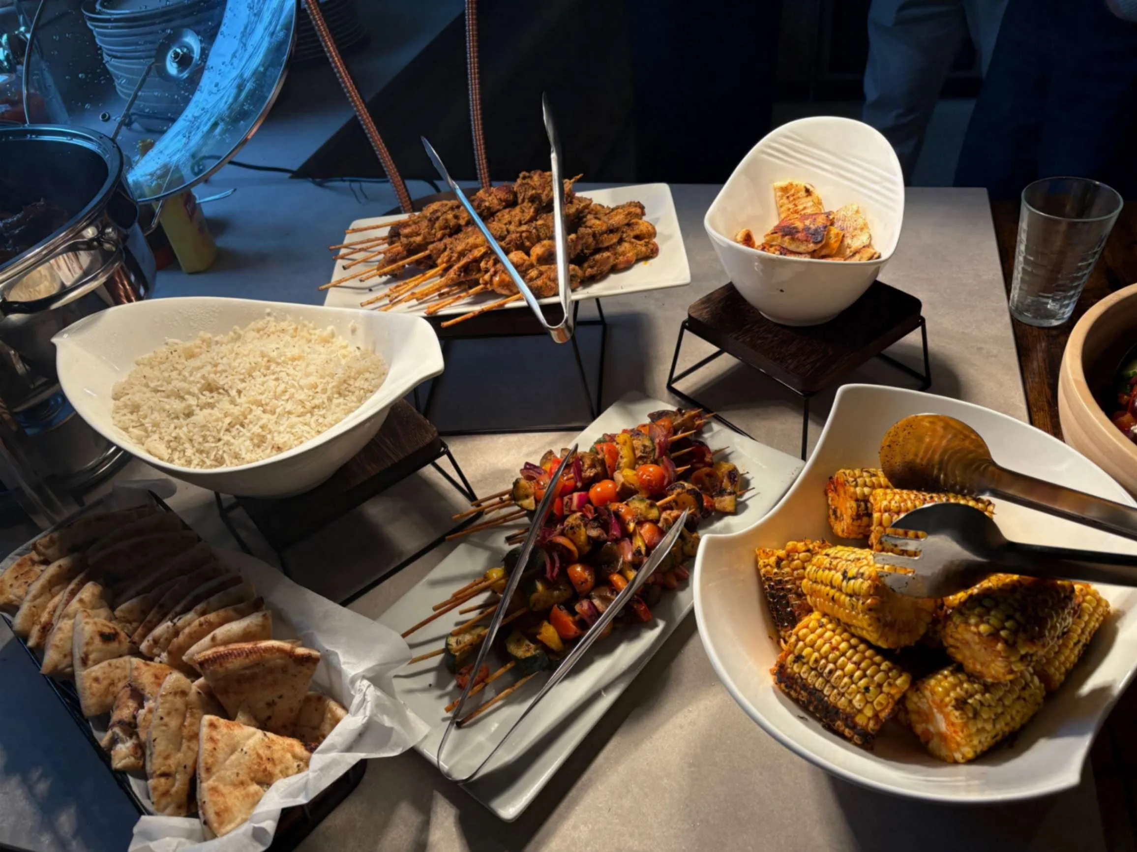 Greek Tings barbecue buffet with skewers, grilled vegetables, corn, rice and pita bread.