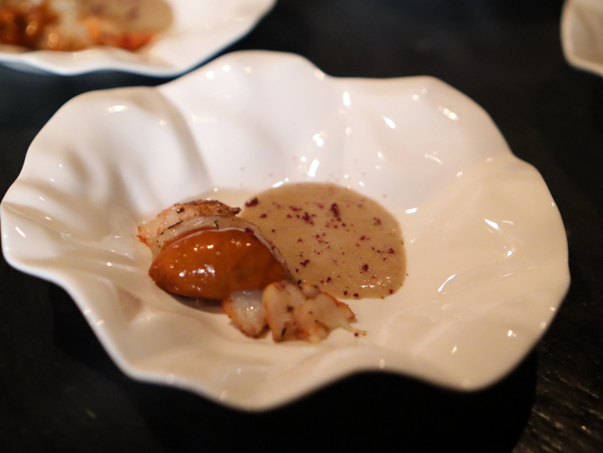 Small seafood canapé served with glossy orange sauce and creamy purée.