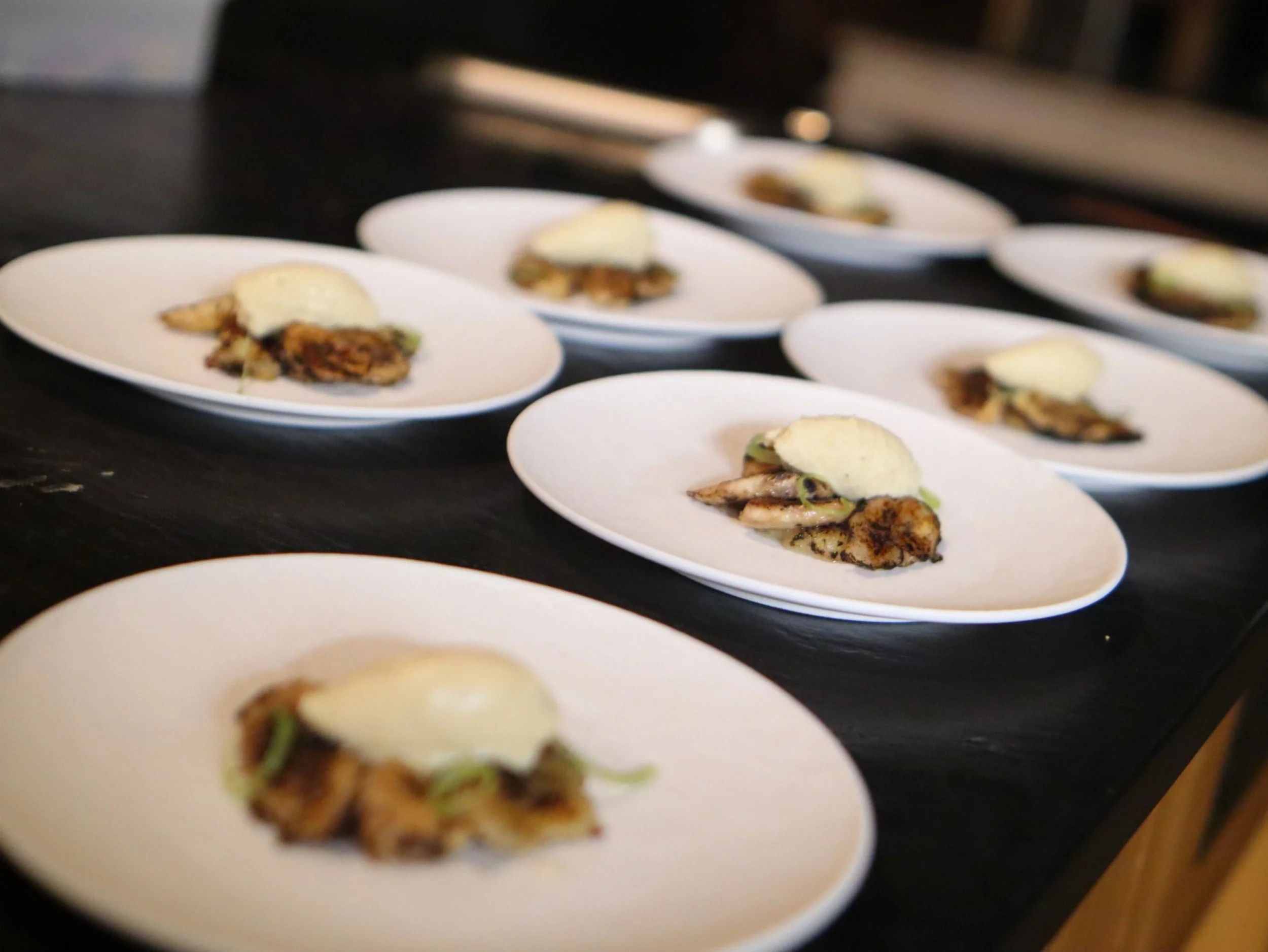  Rows of plated seafood starters with delicate garnish ready for private dining service.

