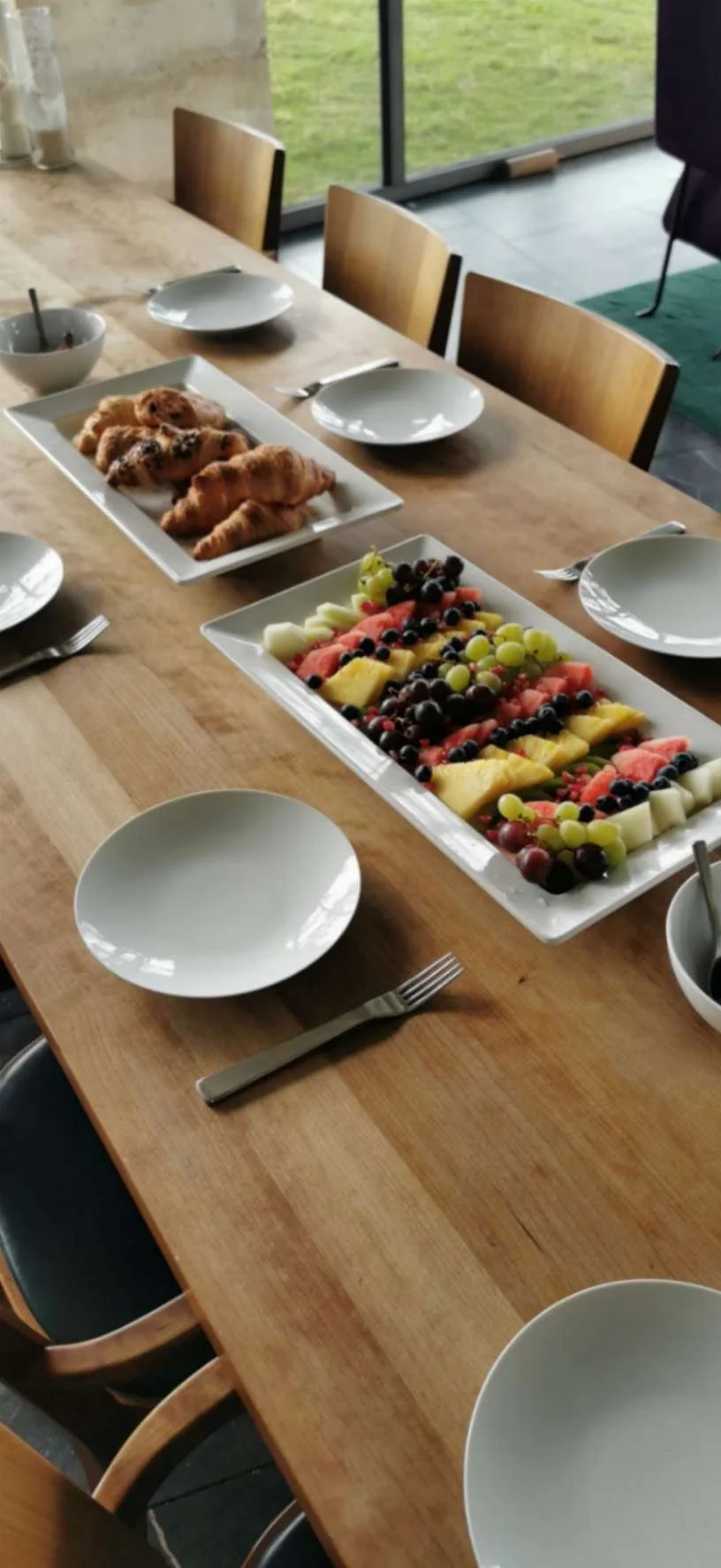 Private breakfast table with croissants, pastries and a large fresh fruit platter.
